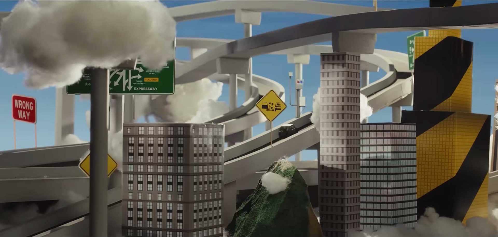 A complex tangle of highways with signs, surrounded by modern buildings and clouds, with a mountain and a Wrong Way sign in the foreground—an urban scene reminiscent of Joel Kefali’s distinctive style, perhaps serving as a visual metaphor for navigating life’s roads with AA Insurance. Frame from Stash Magazine article.