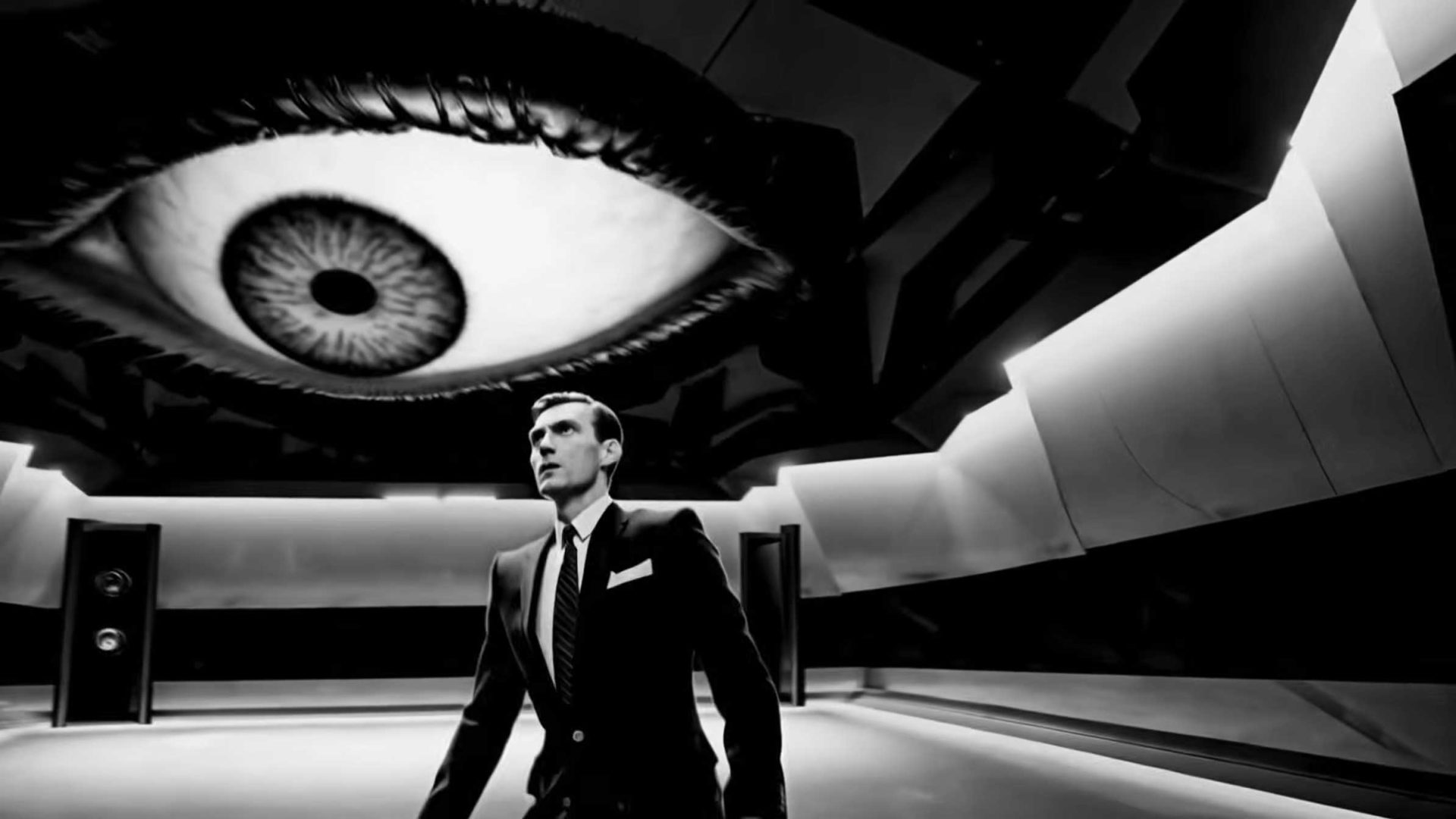 A man in a suit stands in a futuristic room with a giant eye on the ceiling, creating an intense, dramatic atmosphere reminiscent of Alessandro Bavari’s surreal style. Solid Light From Space cuts through the black and white scene, heightening the sense of otherworldly tension. Frame from Stash Magazine article.