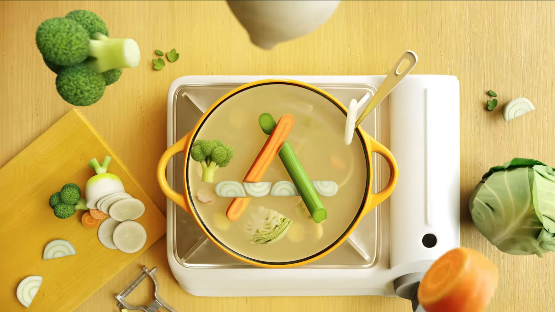 Top view of a yellow pot on a stove with boiling vegetable soup—carrots, broccoli, celery, and onions. Nearby are chopped veggies, cabbage, peeler, and cutting board on a yellow surface; the scene evokes a vibrant Apple Japan ad by Psyop. Frame from Stash Magazine article.