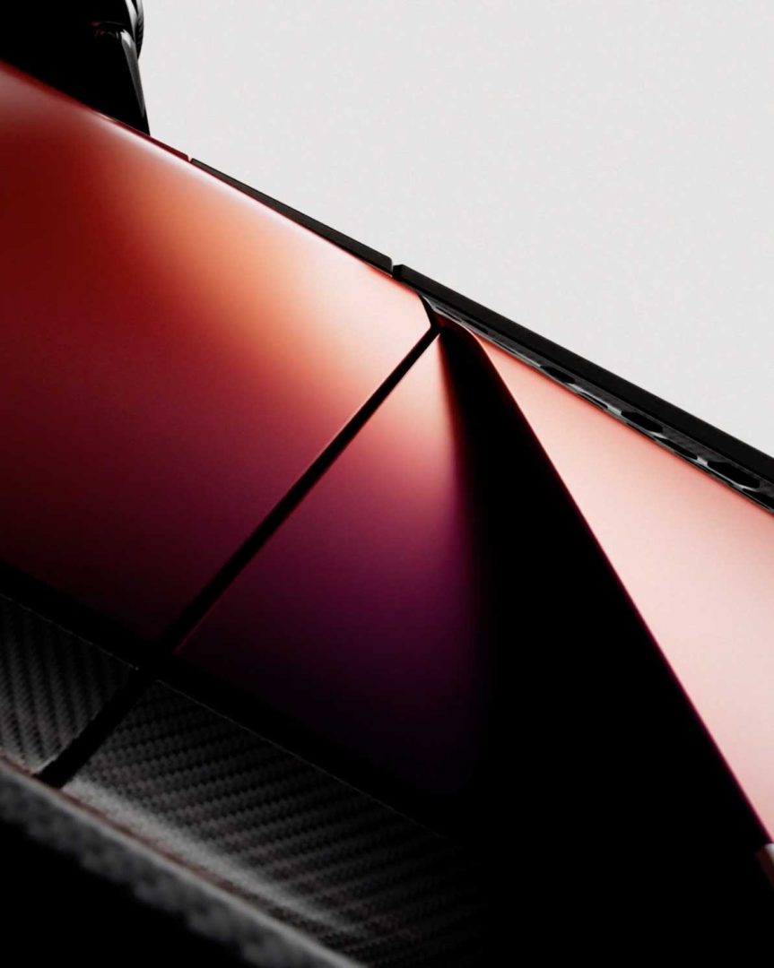 Close-up of a geometric structure with red, metallic panels and sharp angles, likely part of a modern Valen Supercar, against a plain light background. Frame from Stash Magazine article.