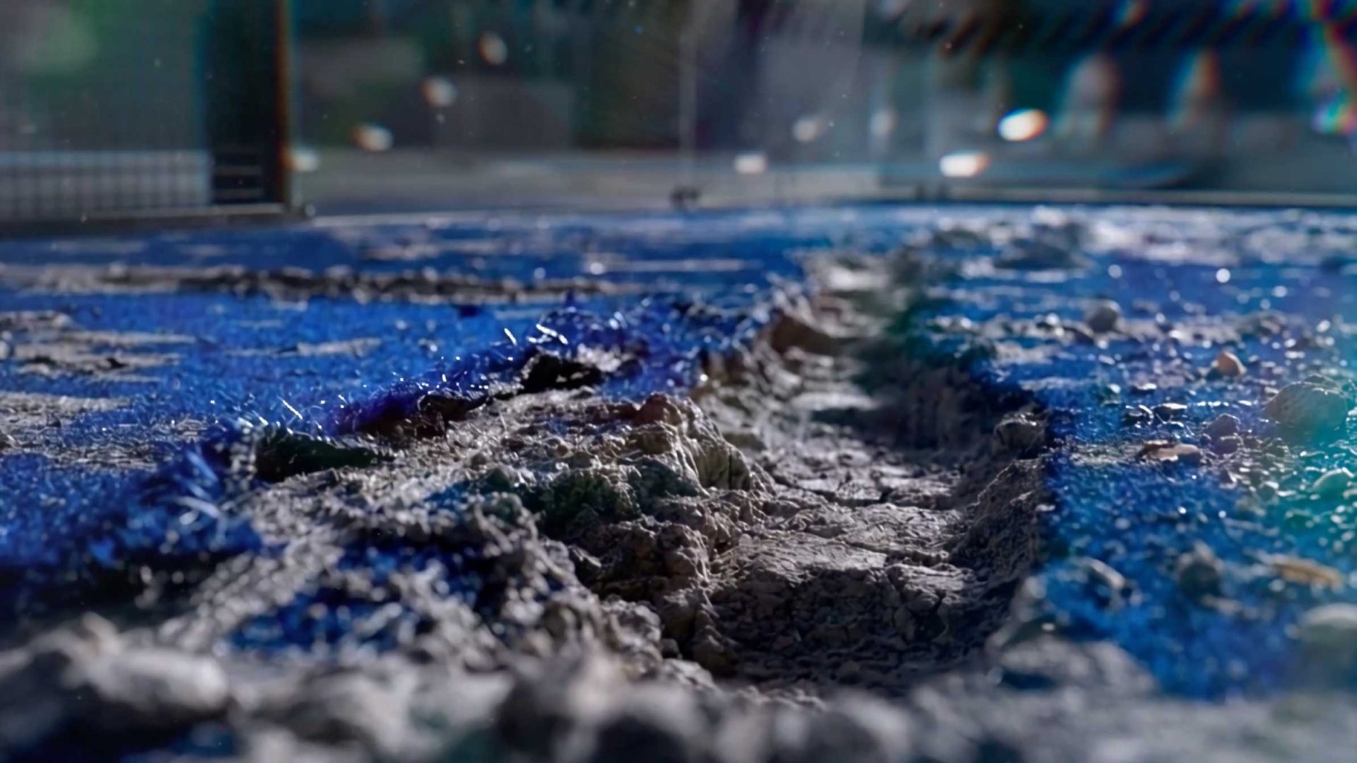 A close-up view of a deep crack running through the blue, textured surface of a Bullpadel Xplo 02 padel racket. Frame from Stash Magazine article.