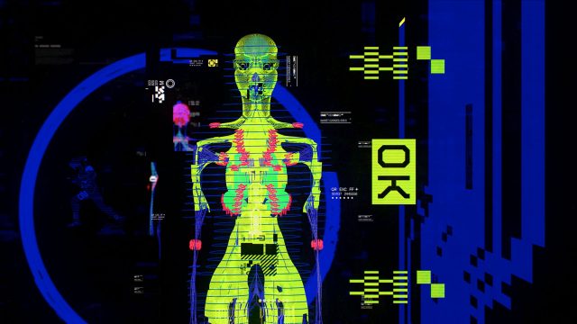 A digital artwork shows a neon green human skeleton with red and blue accents, surrounded by data graphics and a yellow OK label on the right against a dark, glitchy background. The phrase “You Are Dead” is subtly integrated into the scene, giving it a cinematic edit that heightens its intensity. Frame from Stash Magazine article.