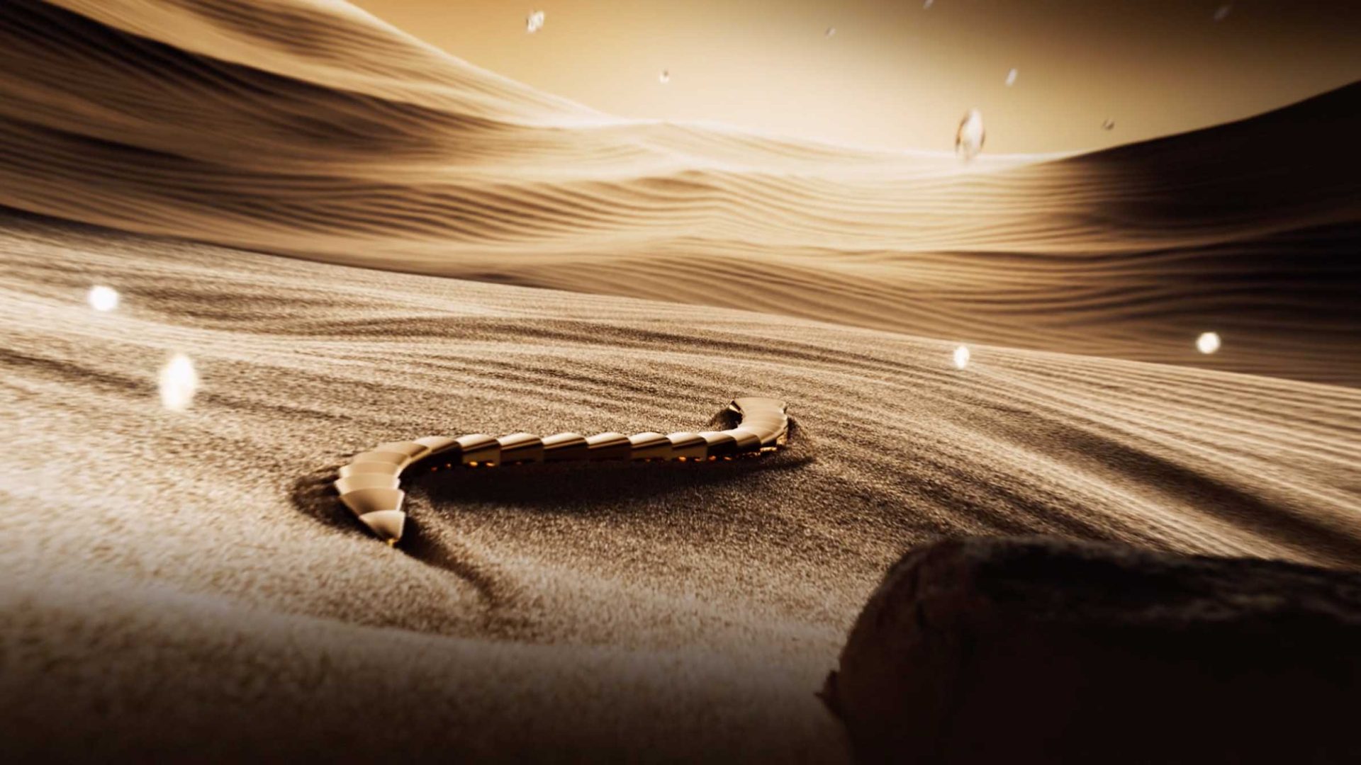 A segmented, robotic creature reminiscent of the Bvlgari Serpenti glides across sandy dunes under a sepia sky, with glowing particles floating in the air—a striking scene worthy of a Spec Spot by Vladislav Evdokimov. Frame from Stash Magazine article.