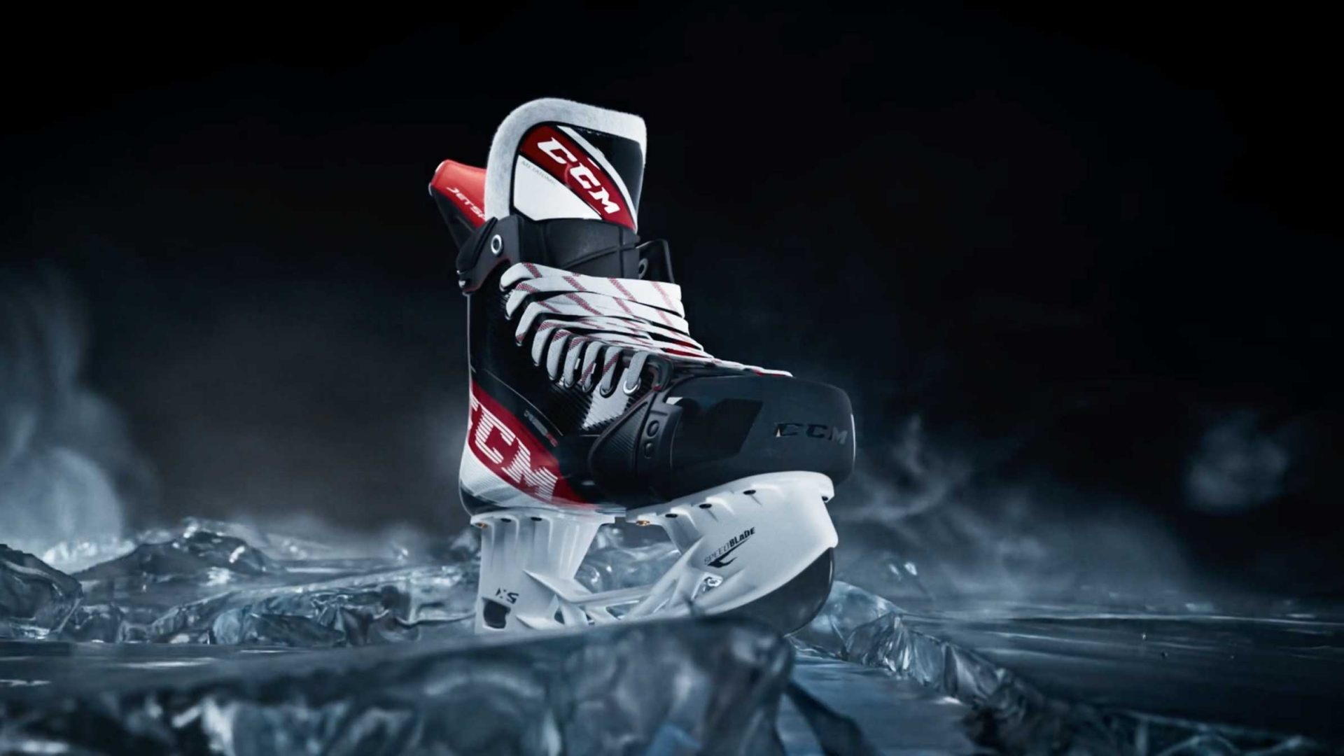 A single CCM Jetspeed hockey skate with red, white, and black accents is displayed on an icy surface, surrounded by mist and dramatic lighting in a striking commercial setting. Frame from Stash Magazine article.