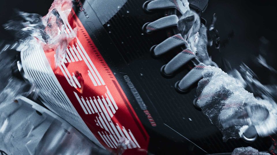 Close-up of a black and red athletic shoe in motion, surrounded by splashing water and ice, capturing dynamic energy and Blades of Glory style in every detail—perfect for a CCM Spec Spot. Frame from Stash Magazine article.
