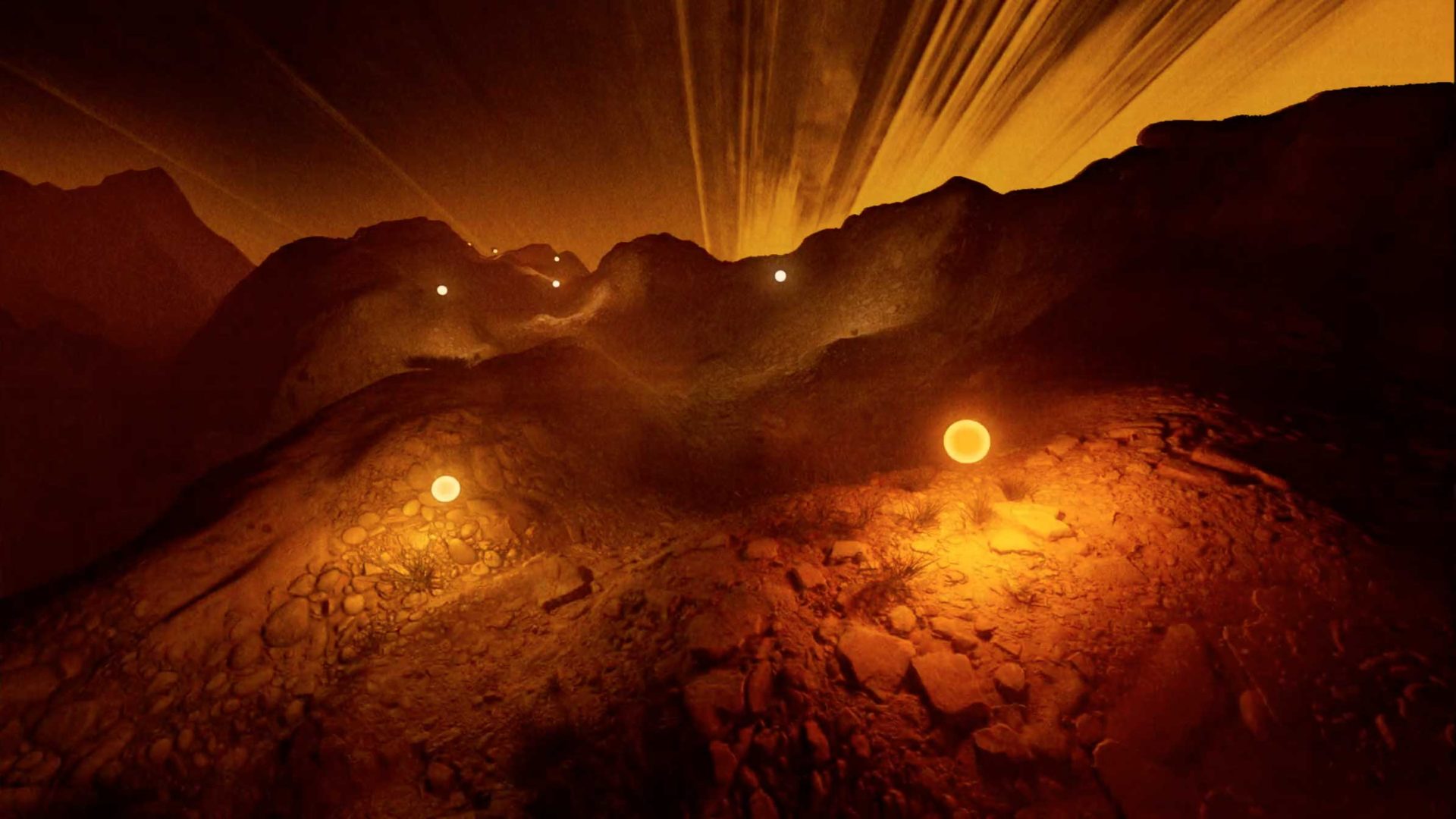A rocky, mountainous landscape under a dramatic sky with glowing orange spheres lighting a winding path at night, capturing the interplay of sound & light that animates this breathtaking geography. Frame from Stash Magazine article.