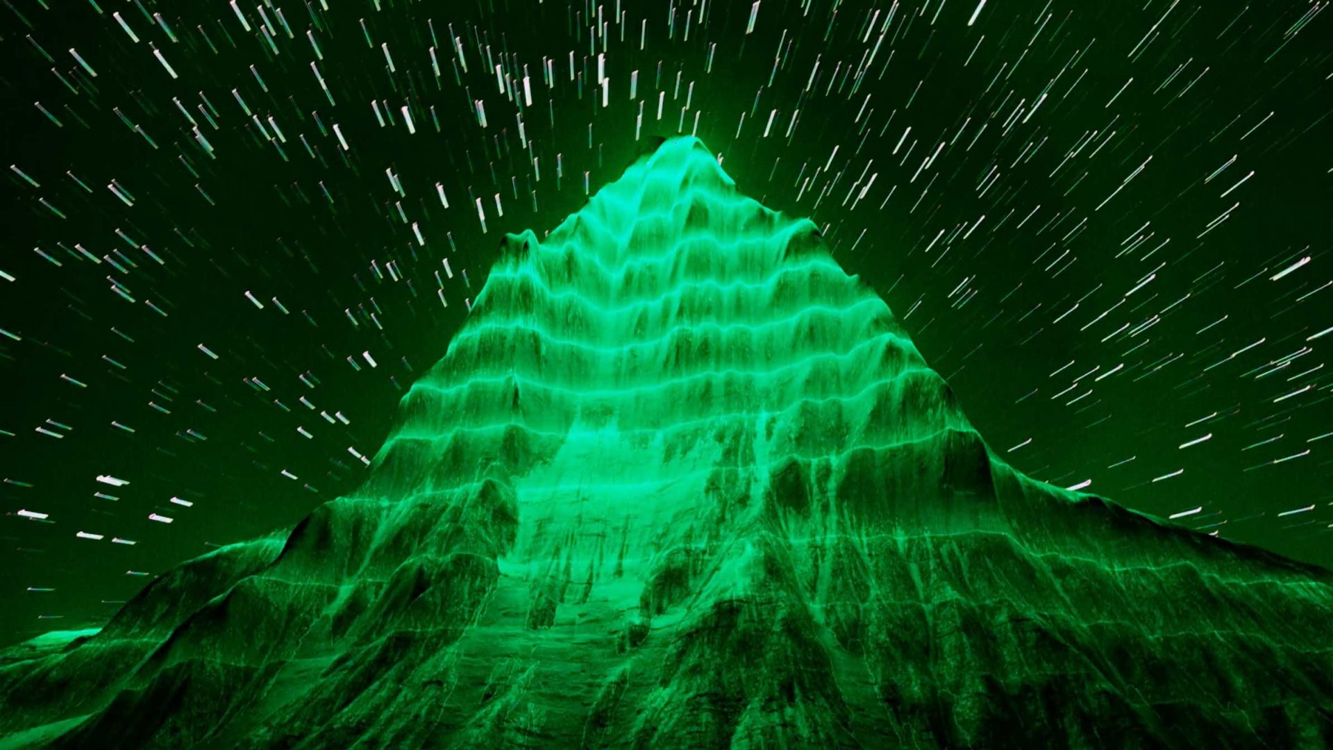 A green-lit, pyramid-shaped mountain with horizontal ridges, set against a night sky with streaking star trails, creates a surreal, otherworldly effect reminiscent of the striking visuals found in the DEEP GEO short film by Kim Taylor. Frame from Stash Magazine article.
