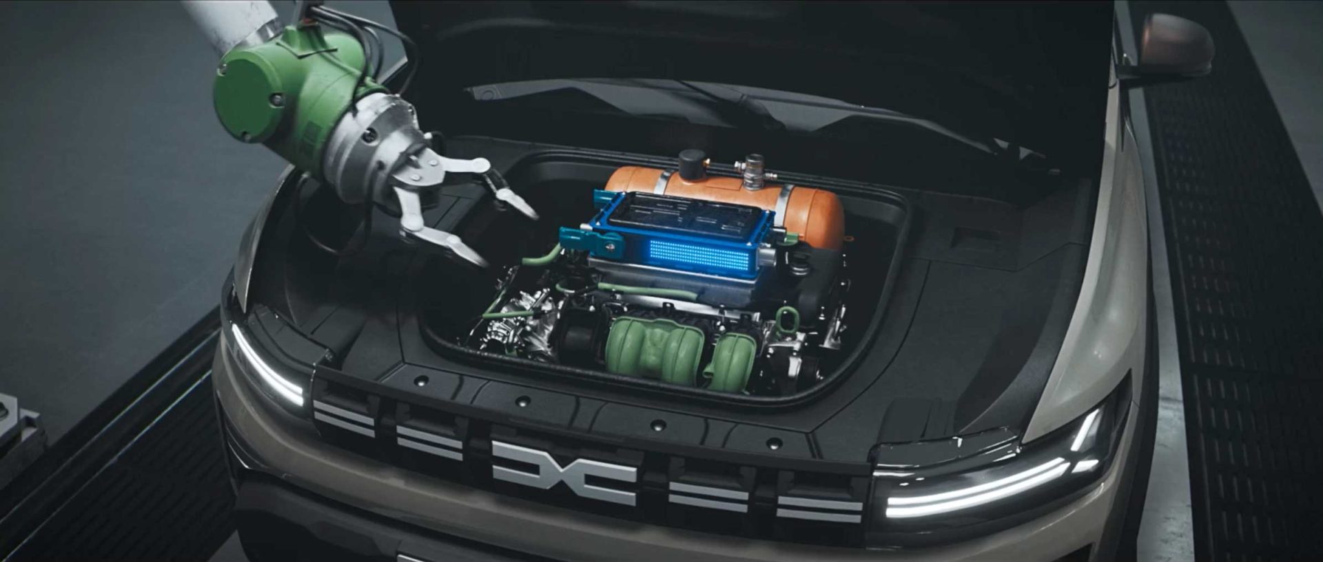 A robotic arm, reminiscent of the Dacia Robots commercial by Romain Chassaing, works on the engine of an electric vehicle with its hood open, revealing colorful components in blue, orange, and green. Frame from Stash Magazine article.