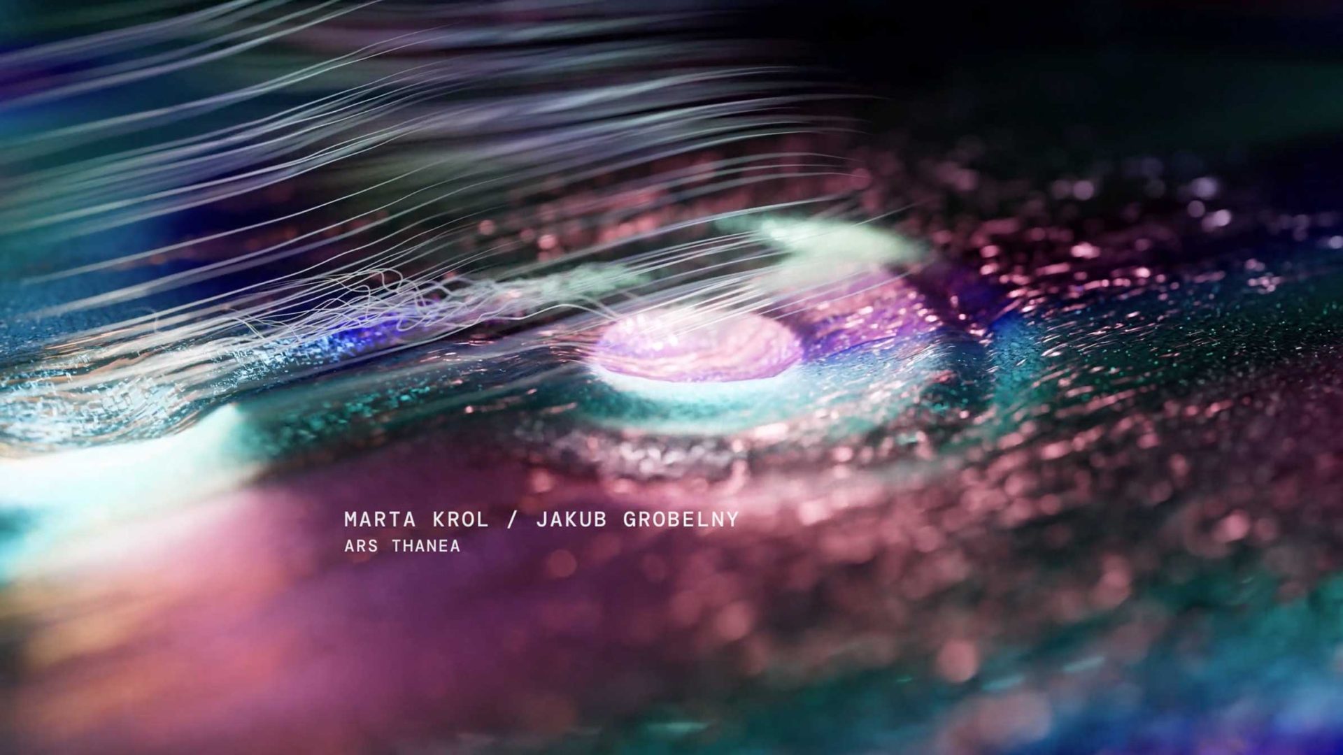 Colorful abstract digital artwork with swirling light patterns, a glowing central orb, and shimmering textures. The text reads “Marta Krol / Jakub Grobelny, Ars Thanea” near the bottom center, created for Digital Design Days Milano 2026. Frame from Stash Magazine article.