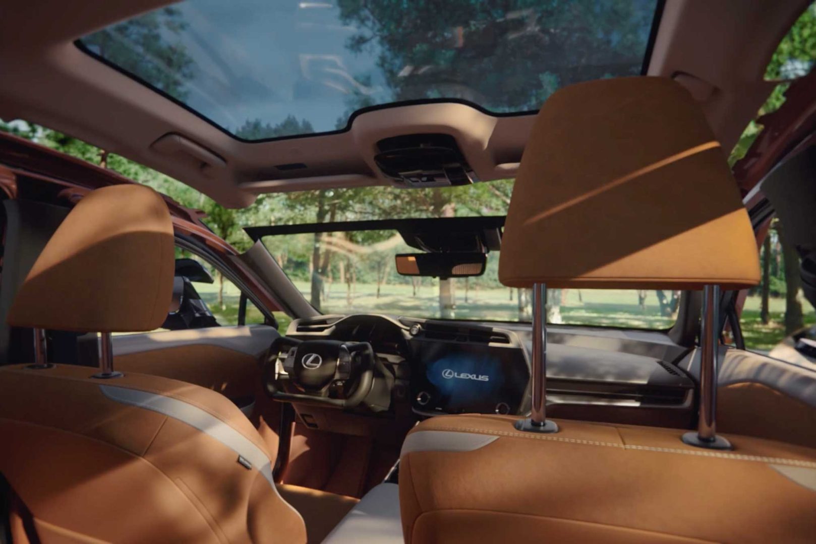 View from the back seat of a Lexus RZ with tan leather interior, panoramic sunroof, and digital dashboard; lush trees and greenery frame the scene, capturing every detail in this serene setting. Frame from Stash Magazine article.