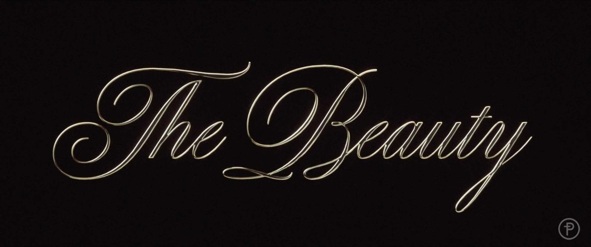 Elegant cursive gold text on a black background reads The Beauty, reminiscent of Kyle Cooper’s iconic title designs crafted at Prologue. Frame from Stash Magazine article.