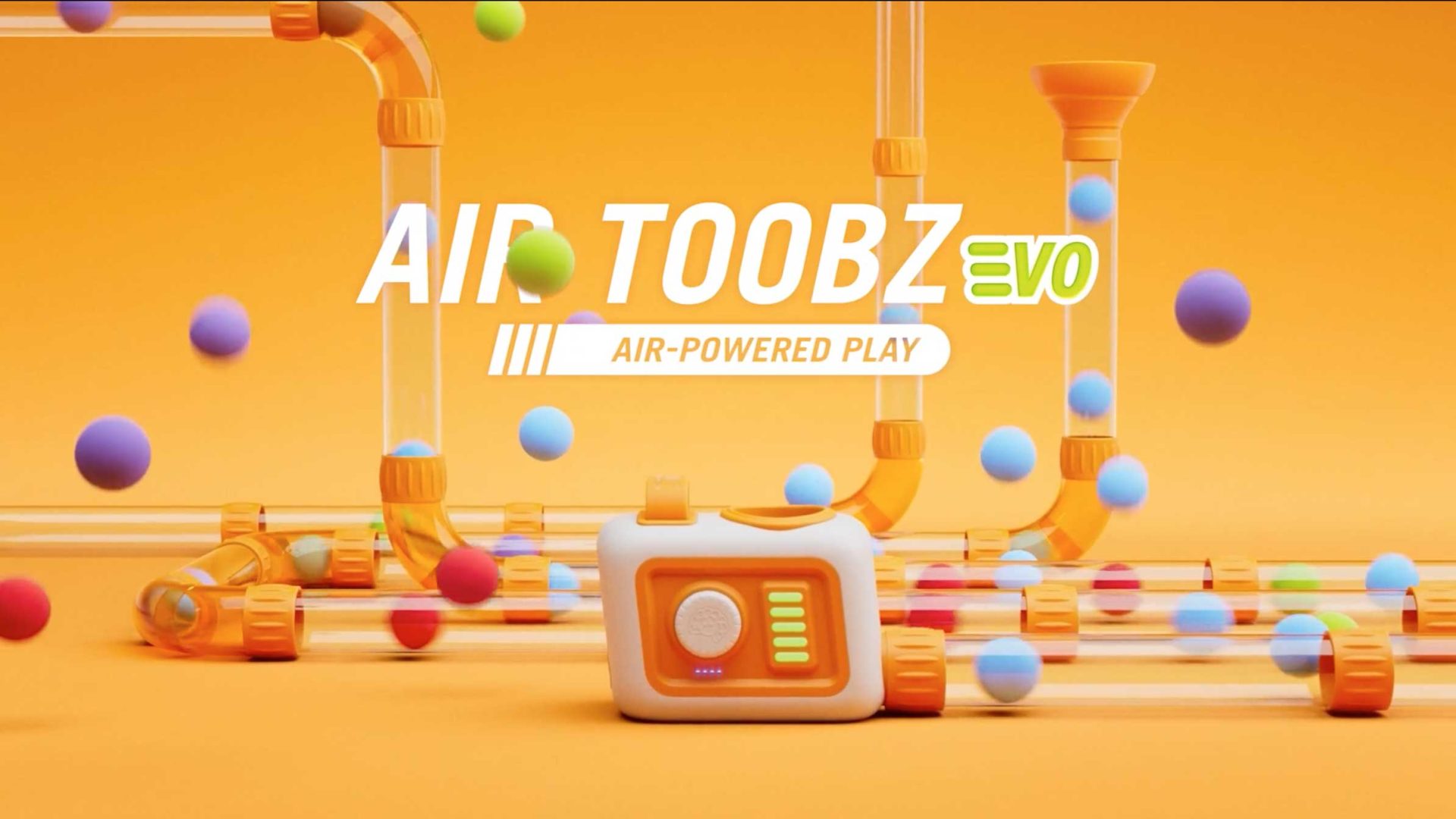 Colorful plastic tubes with bouncing balls surround a white and orange device on an orange background. The text reads, AIR TOOBZ evo AIR-POWERED PLAY. Created in collaboration with Frame48 and Fat Brain Toys, the scene is bright and playful, suggesting a lively toy or game. Frame from Stash Magazine article.