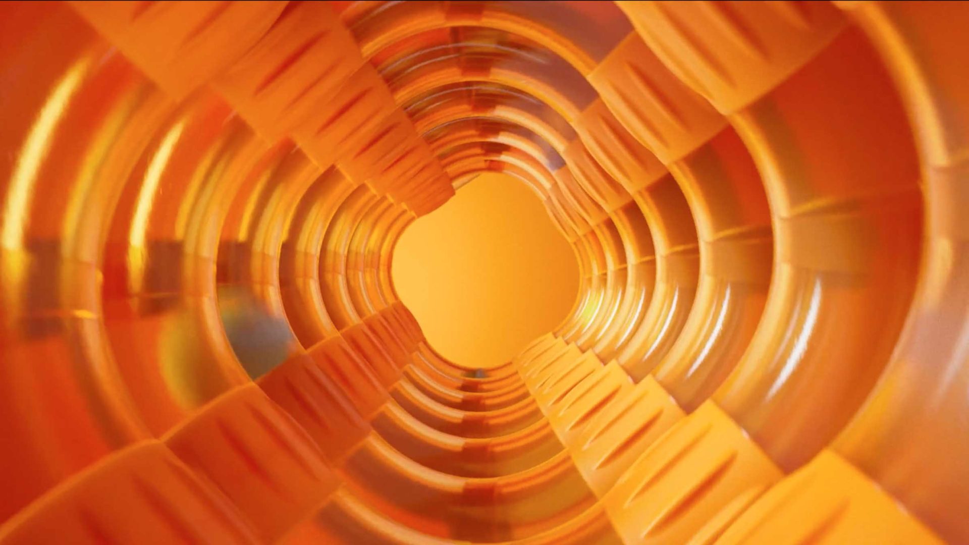 View through the inside of an orange plastic tunnel or tube, such as the Air Toobz from Fat Brain Toys, showing repeating ridges and a bright central opening. Frame from Stash Magazine article.