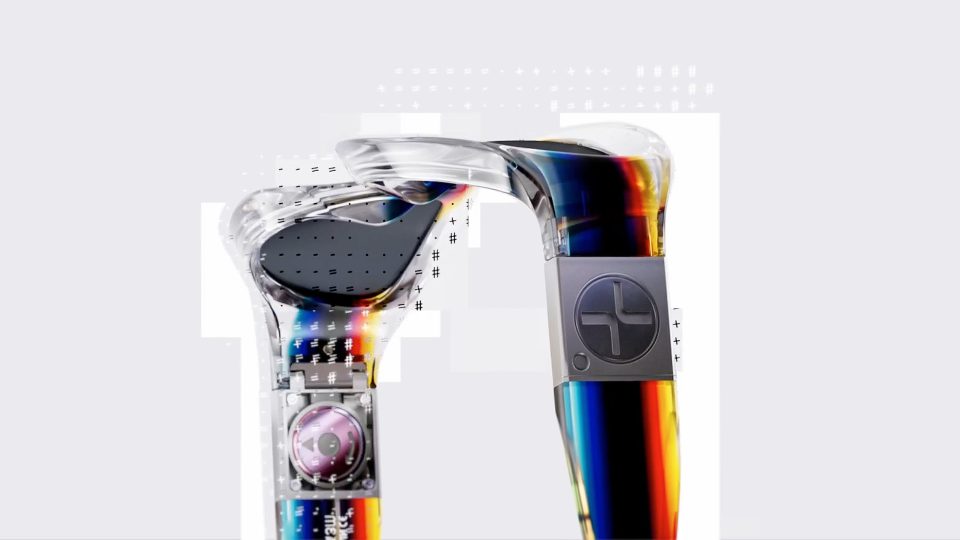 Two transparent, futuristic ear-worn devices from the Felipe Pantone x Etnia Barcelona brand film with visible internal components and a rainbow-gradient finish. Frame from Stash Magazine article.