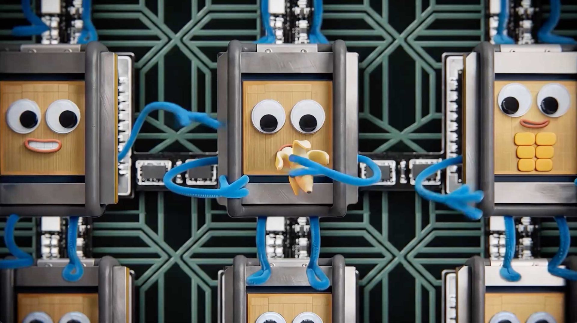 A cartoonish robot with googly eyes and blue arms stands in front of a geometric patterned background, holding a banana—a playful nod to Laurie Rowan's whimsical style. Other similar robots with different expressions are visible around it. Frame from Stash Magazine article.