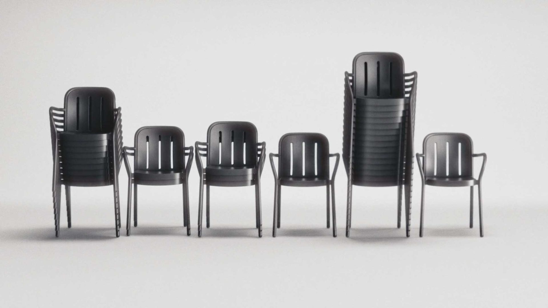 Six black HAY chairs are aligned in a row. Three of the chairs are stacked in piles of increasing height from left to right, while the other three FRAME chairs stand alone. The background is plain white. Frame from Stash Magazine article.