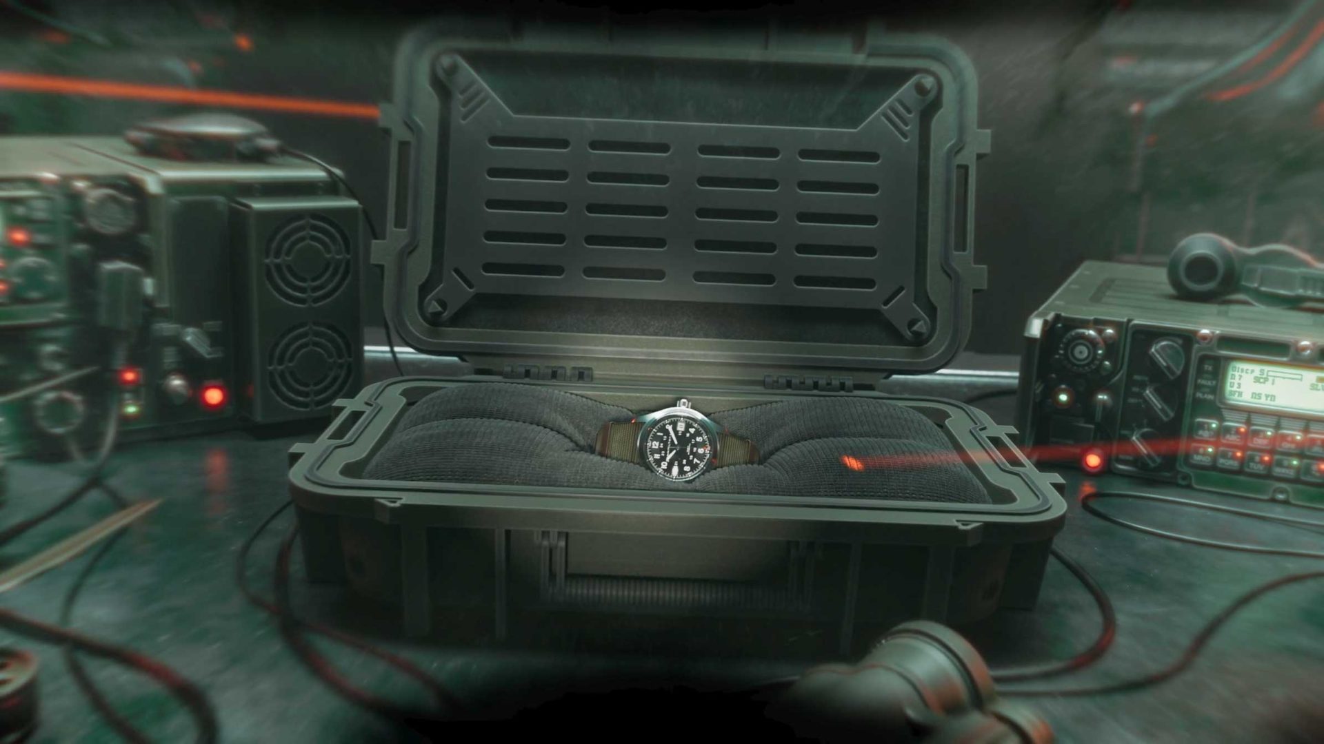 A Hamilton wristwatch with a dark strap is displayed inside an open, padded protective case, surrounded by electronic devices and wires on a dimly lit table—evoking the cinematic feel of a brand film. Frame from Stash Magazine article.