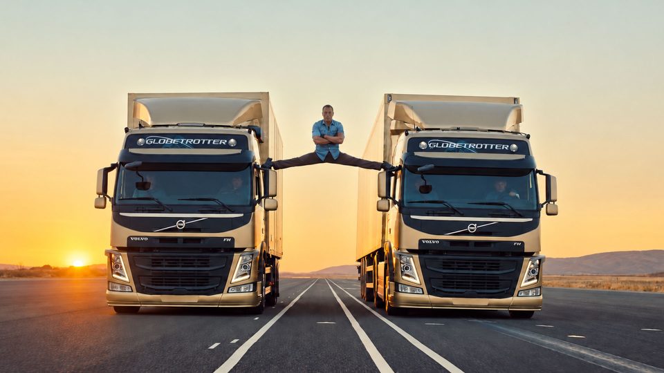 A person performs a split between two moving Volvo trucks on an empty road at sunset, with the parallel trucks in a dramatic shot created by Swedish visual effects studio SWISS. Frame from Stash Magazine article.
