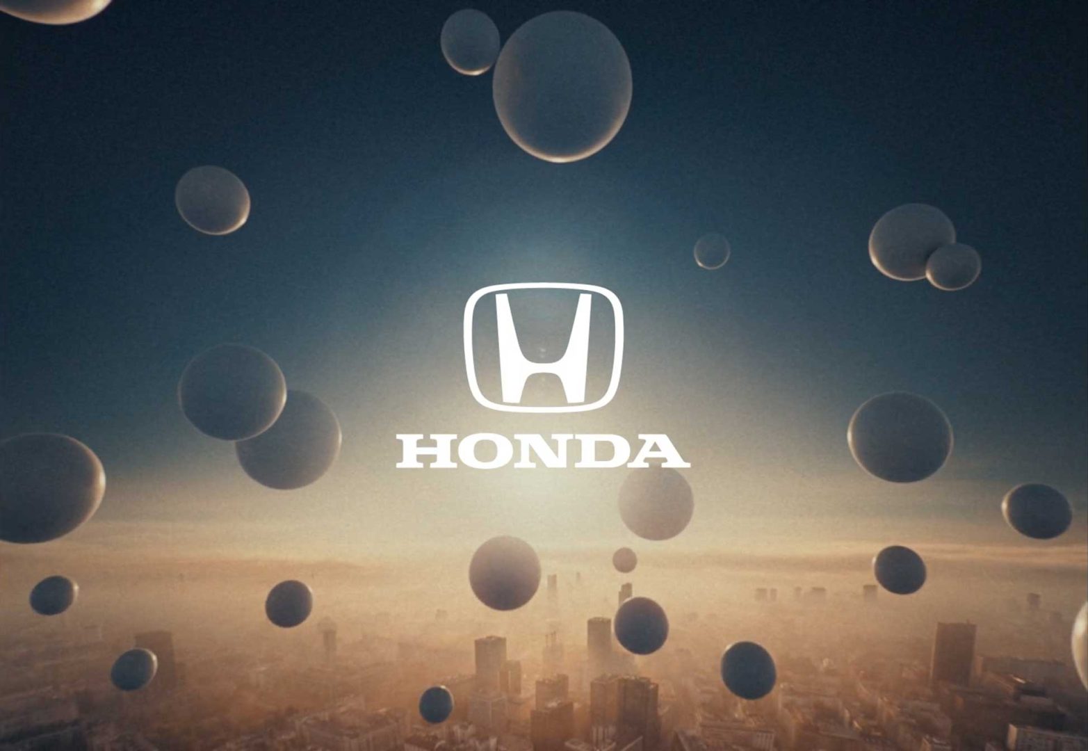 Floating spheres drift above a hazy cityscape with the white Honda logo and HONDA text centered in the foreground against a sunrise or sunset sky, embodying engineered dreams that soar like a Black Kite on the horizon. Frame from Stash Magazine article.