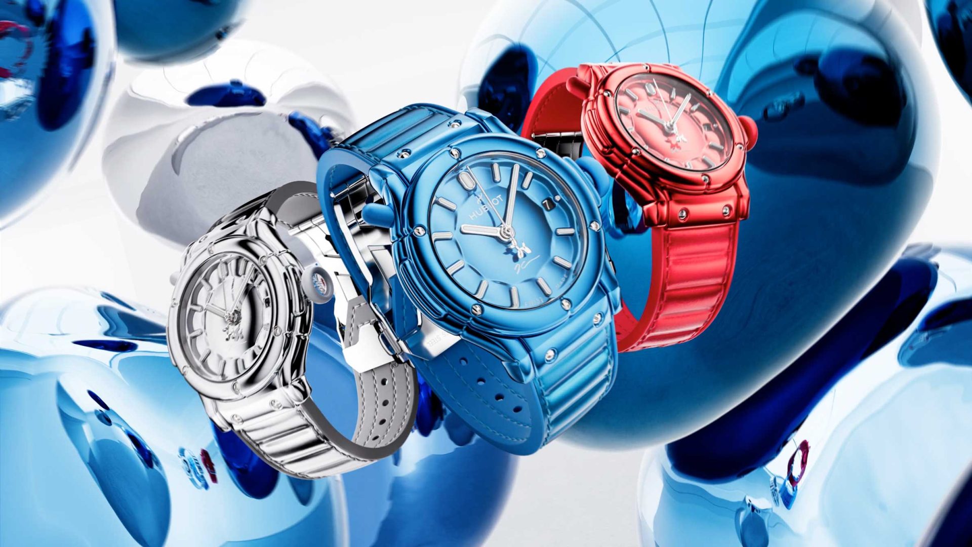 Three wristwatches—silver, blue, and red—are displayed against a background of reflective blue and silver orbs. Inspired by the Hublot Classic Fusion Balloon Dog by Jeff Koons, the watches feature metallic bands and sleek, modern designs. Frame from Stash Magazine article.