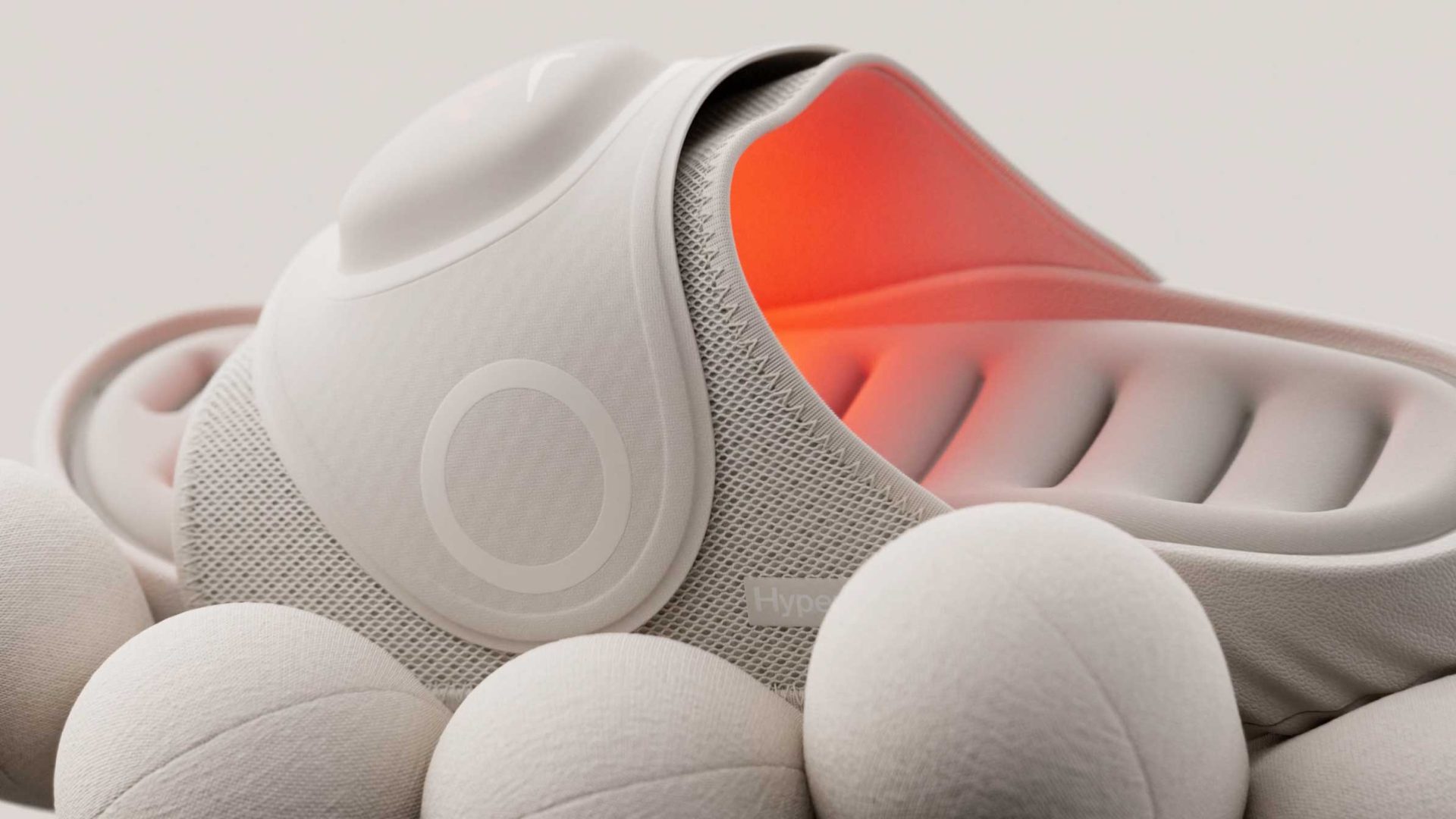 Off-white Hyperslide recovery slide with a glowing orange interior, resting on several off-white spheres. Frame from Stash Magazine article.