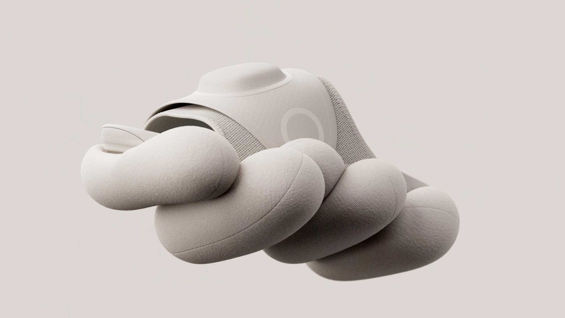 A beige, fabric-covered Hyperslide wearable device with a rounded, pillowed base. Frame from Stash Magazine article.