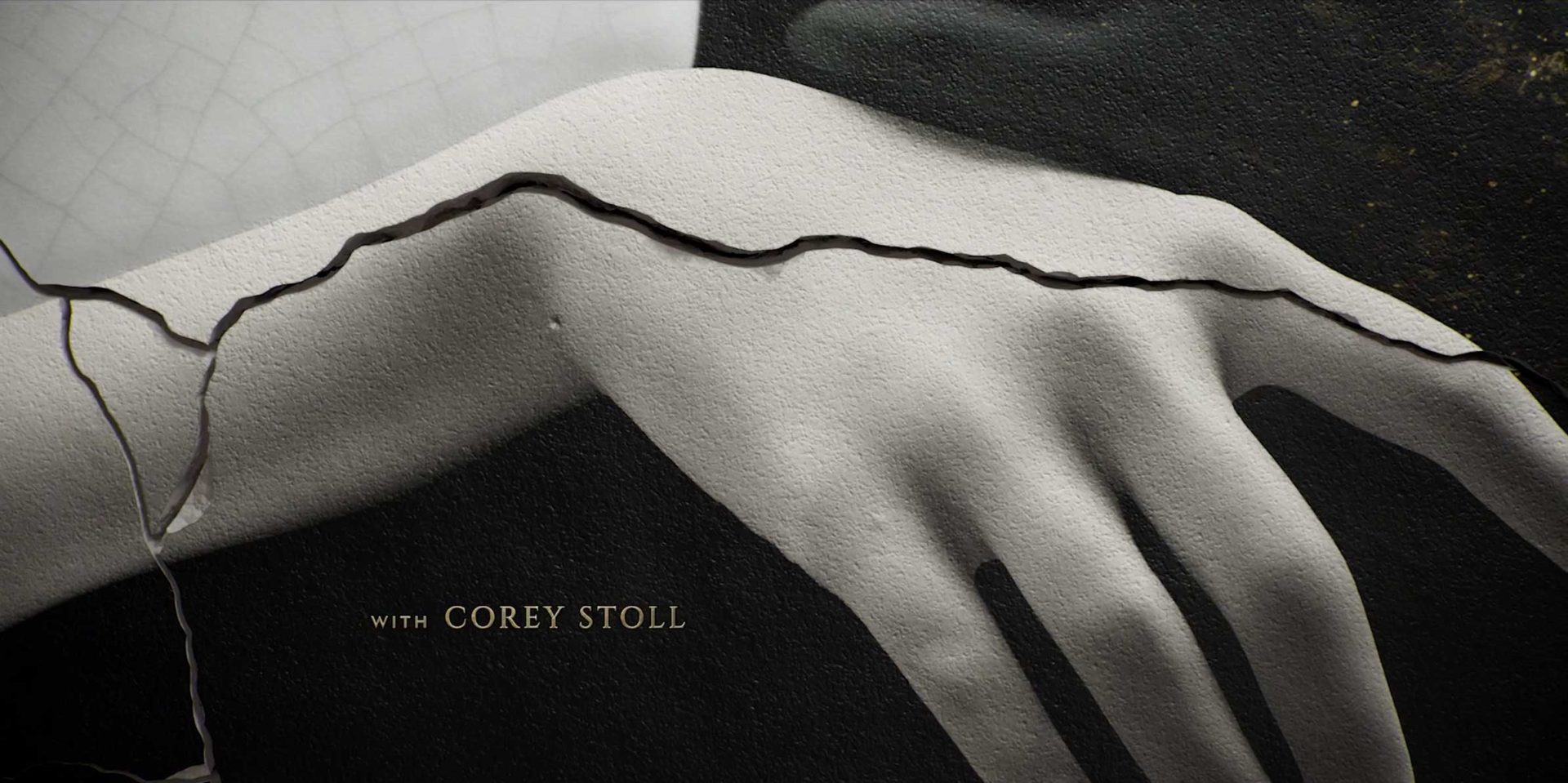 A close-up of a pale, sculpted hand with dark cracks running across it; the text WITH COREY STOLL appears in gold letters in the lower left corner, evoking the signature style of Imaginary Forces and Karin Fong for Apple TV+. Frame from Stash Magazine article.