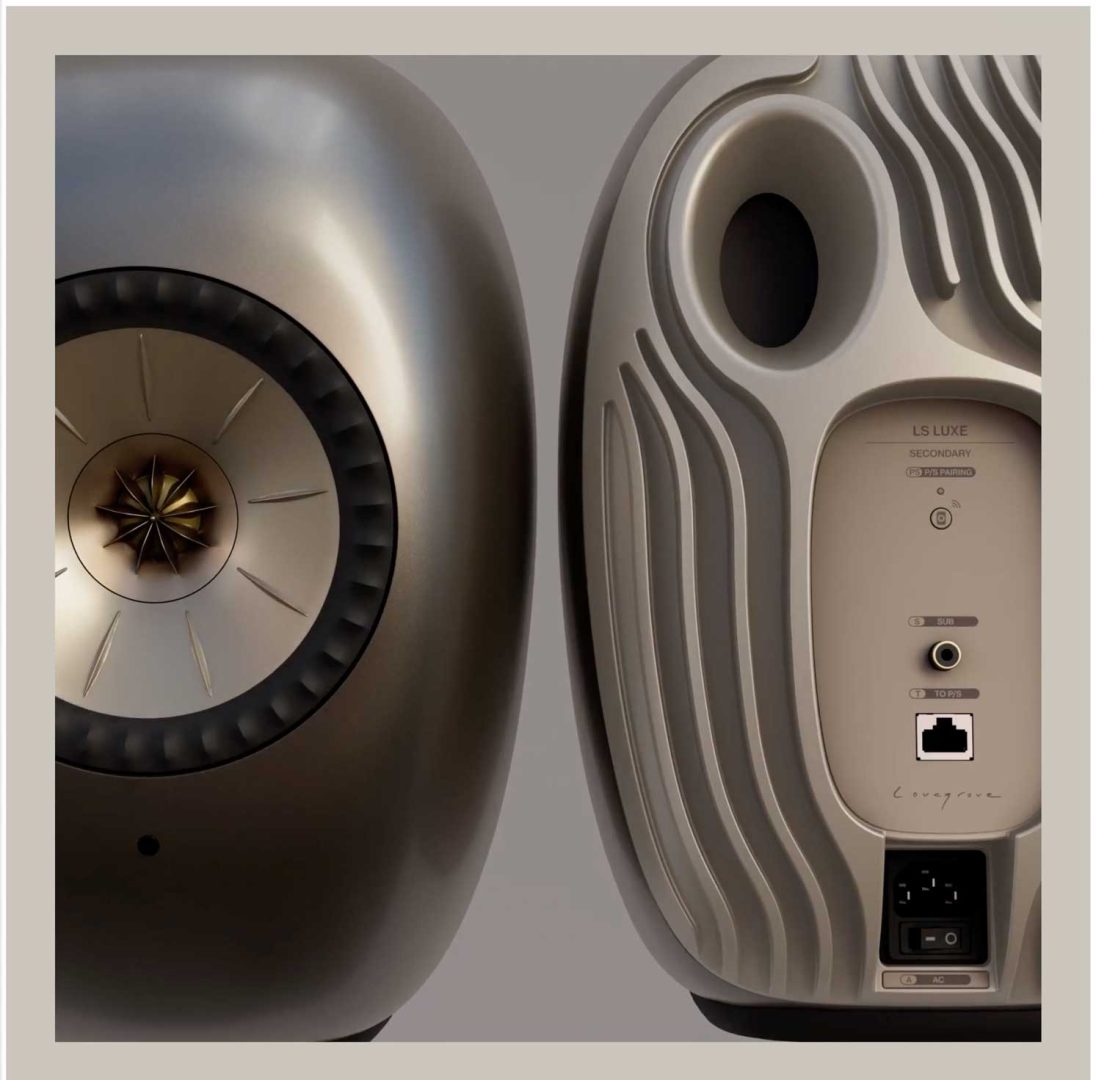 Two modern, metallic speakers from KEF are shown front and back; the front sports a star-shaped center, while the back features textured grooves, an input panel with ports, and a power switch—all set against a neutral background that highlights their LS Luxe design as envisioned by James Brocklebank. Frame from Stash Magazine article.