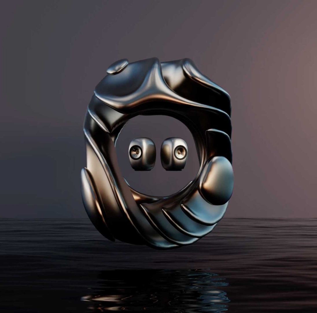 A metallic, abstract circular sculpture with two floating spheres inside, resembling eyes, hovers above a rippling water surface against a dark, gradient background—a striking composition evocative of KEF’s LS Luxe collection and the visionary touch of James Brocklebank. Frame from Stash Magazine article.