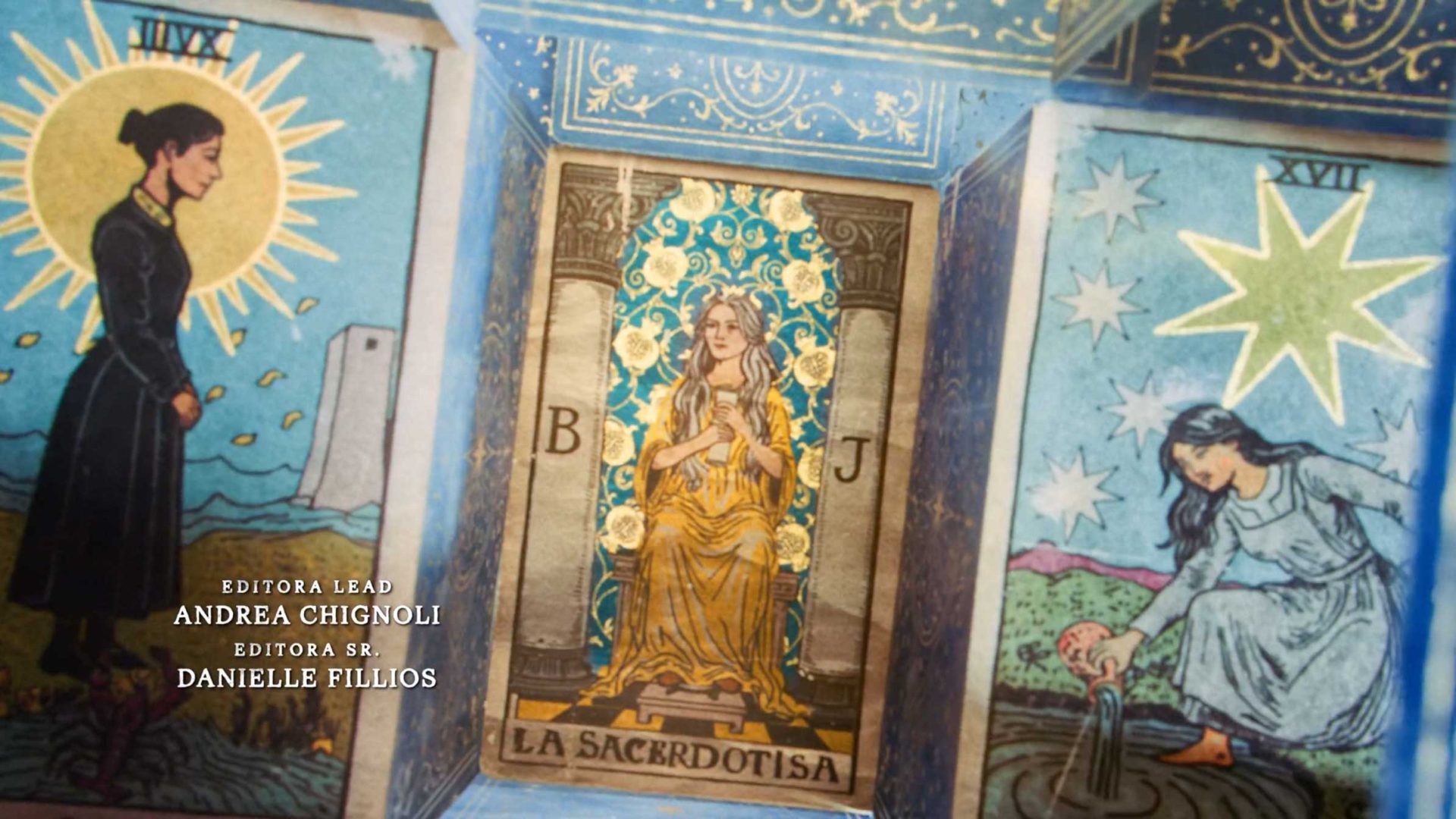 Three tarot cards are shown: The Moon, The High Priestess (La Sacerdotisa), and The Star. At the center, La Sacerdotisa glows amid gold and blue patterns. Credits for Andrea Chignoli and Danielle Fillios appear. Featured on Amazon Prime Video’s La Casa de los Espíritus. Frame from Stash Magazine article.