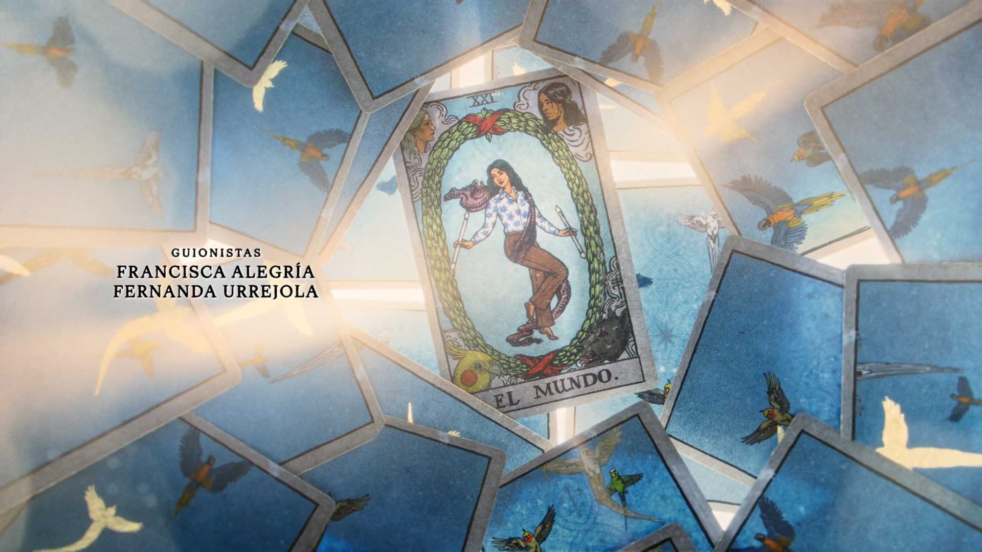 A tarot card labeled EL MUNDO, featuring a woman surrounded by birds, is at the center, with more cards and flying birds around it. The text GUIONISTAS FRANCISCA ALEGRÍA FERNANDA URREJOLA appears on the left, hinting at La Casa de los Espíritus on Amazon Prime Video. Frame from Stash Magazine article.