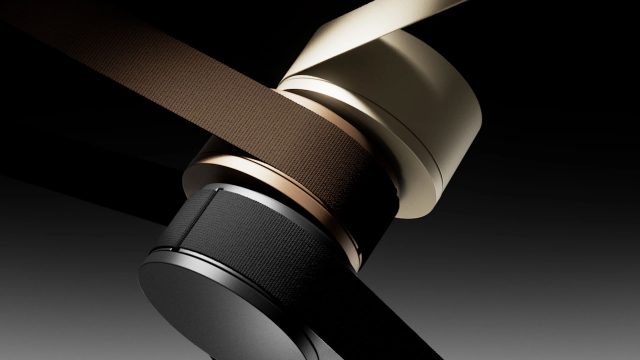 Two cylindrical, modern speakers in black and gold, wrapped with matching fabric straps, are set against a dark gradient background—echoing the sleek, minimalist style of the Lodes MAP lighting product film by jformento. Frame from Stash Magazine article.
