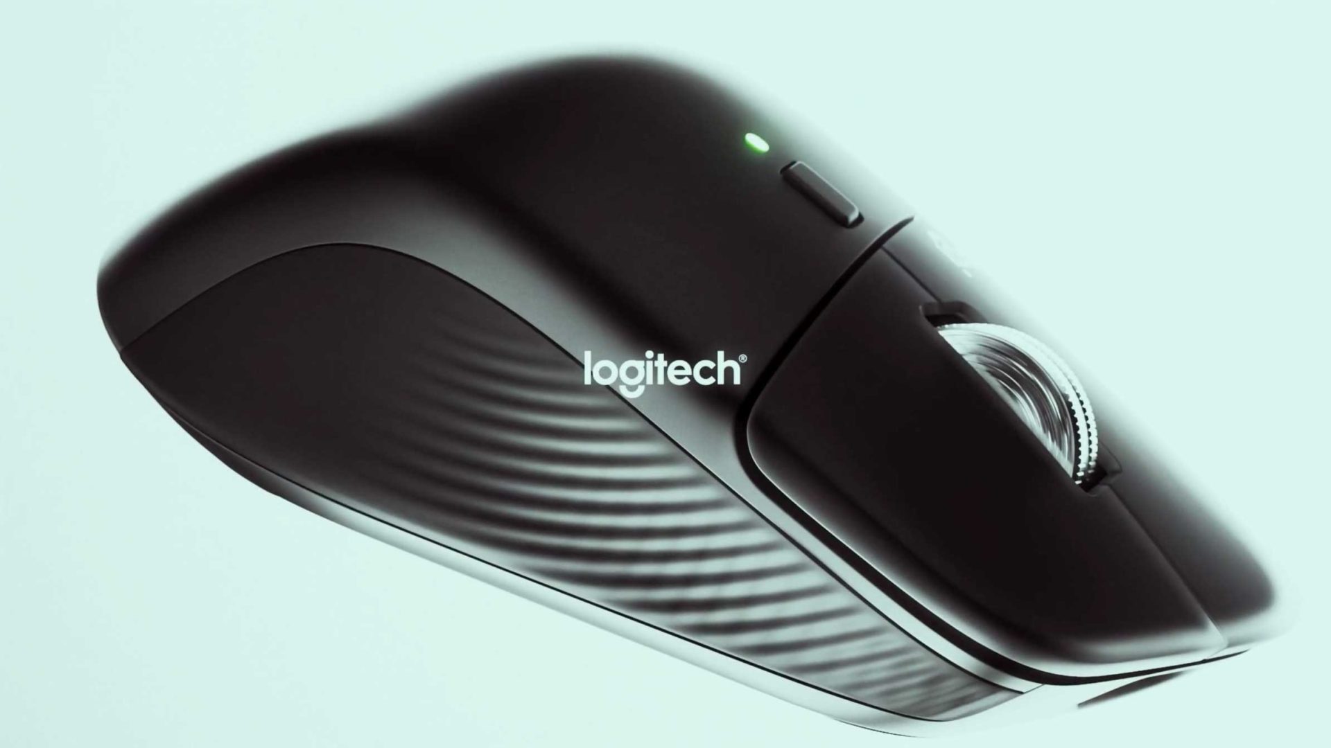 A close-up of a black Logitec MX Master 4 computer mouse with a visible scroll wheel and a green indicator light, set against a light background. Frame from Stash Magazine article.