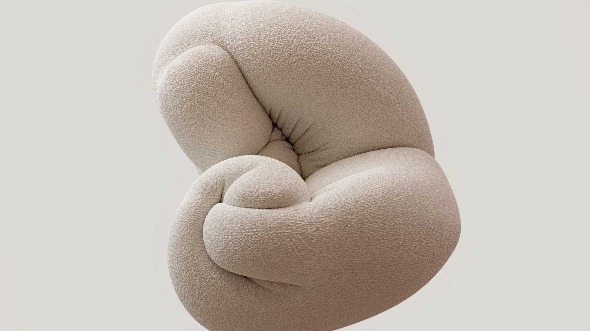 A beige, abstract, plush chair with a twisted, knotted design, resembling soft, intertwined cushions—crafted by Chalk Company and designed by Miles Hellyer—is set against a plain light gray background. Frame from Stash Magazine article.