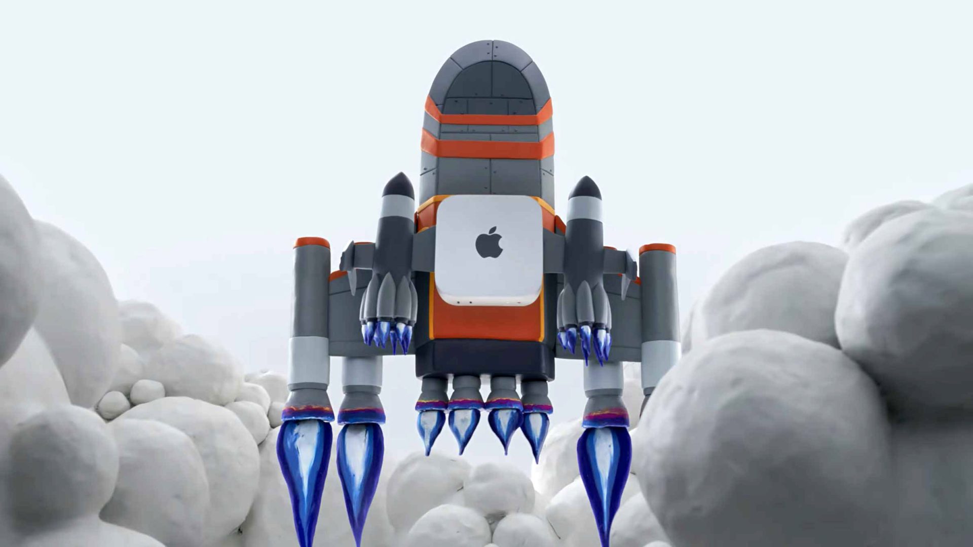 A cartoon rocket with the Apple logo blasts off amid clouds, emitting blue flames from its engines. The rocket has orange and gray colors and a blocky design. Frame from Stash Magazine article.