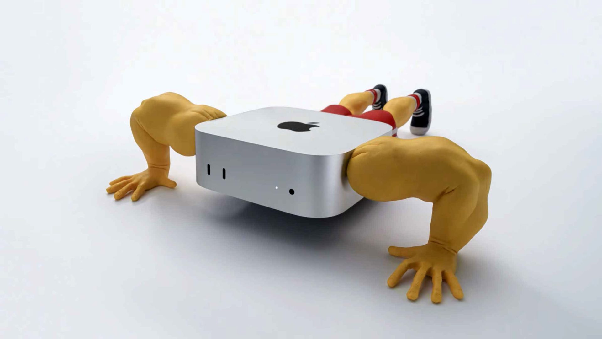 A Mac Mini computer with muscular human arms and legs is doing push-ups on a plain white background. Frame from Stash Magazine article.