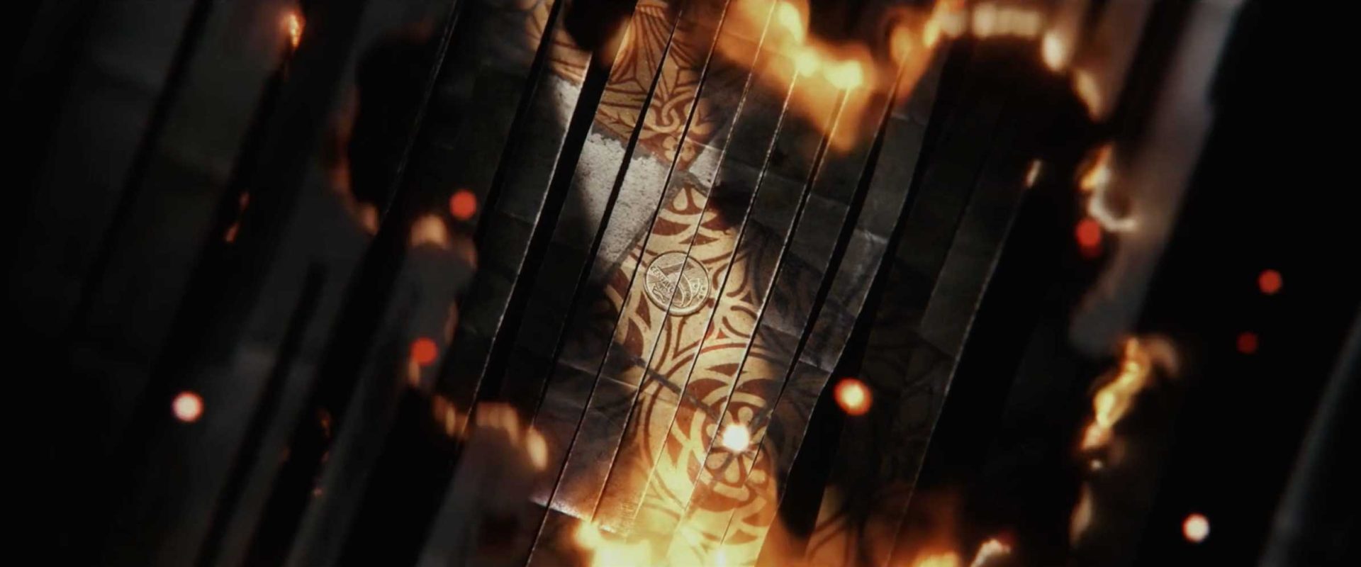 An intricate, golden, floral design is revealed on a metallic surface, surrounded by dark panels and fiery orange glows—evoking the intensity of Man on Fire’s main titles, with glowing embers drifting across the image like a Netflix original. Frame from Stash Magazine article.