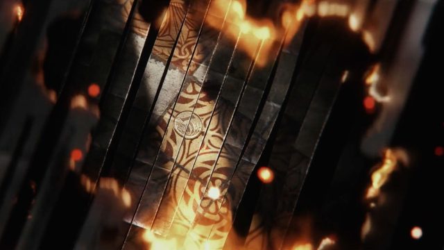 A top-down view of a metallic surface with intricate golden patterns, surrounded by dark panels and glowing orange flames, evokes the intense atmosphere of Man on Fire’s Main Titles for Netflix. Frame from Stash Magazine article.