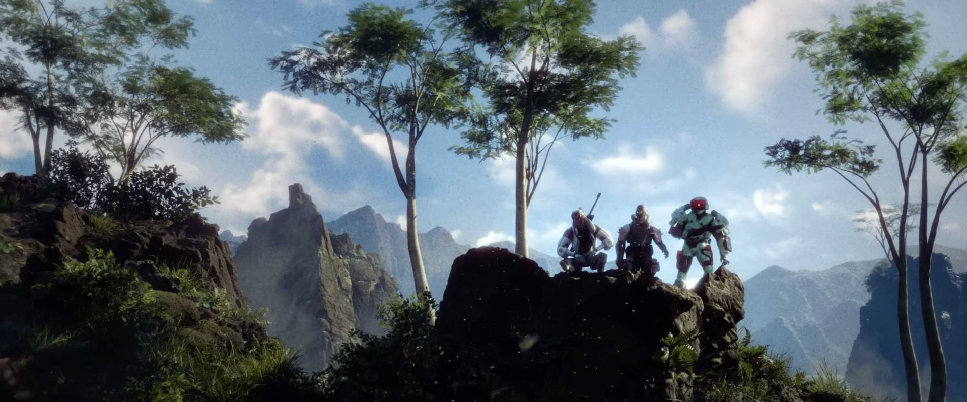 Three armored figures stand on a rocky ledge surrounded by trees and mountains, under a blue sky with scattered clouds. The scene captures a sci-fi atmosphere, evoking the energy of a Marathon Launch amid dramatic natural scenery. Frame from Stash Magazine article.