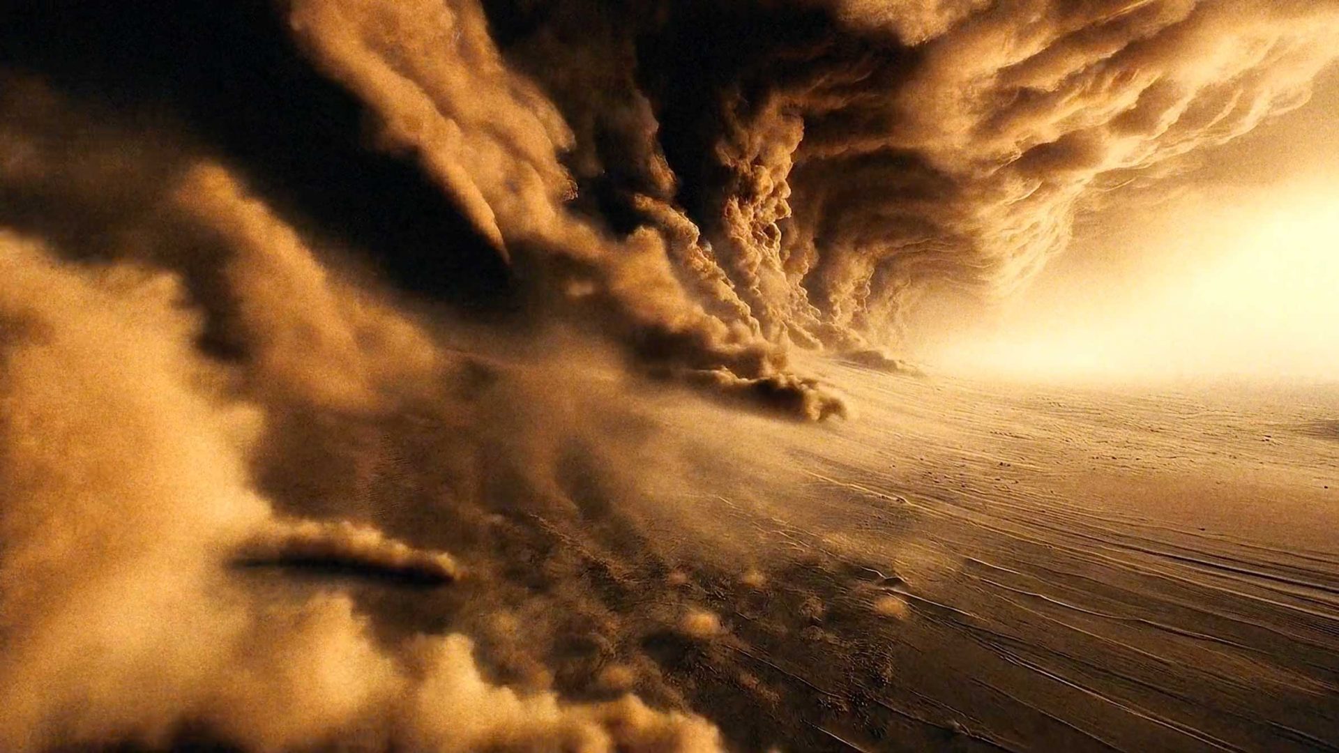 A massive, swirling sandstorm sweeps across a barren desert landscape, with thick clouds of dust and sand obscuring the sky—like an NFL game caught in nature’s fury. The scene is dramatic and intense, with golden-brown tones throughout. Frame from Stash Magazine article.
