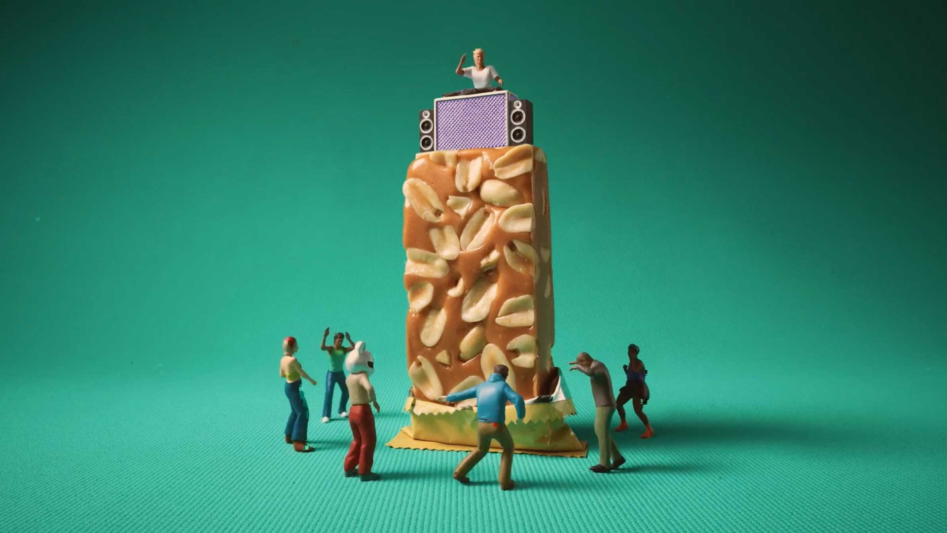 Miniature figures dance around a peanut bar stage, with a tiny DJ and speakers on top, set against a teal background—an imaginative scene inspired by Anthony Farquhar-Smith's playful use of peanuts and nuts. Frame from Stash Magazine article.