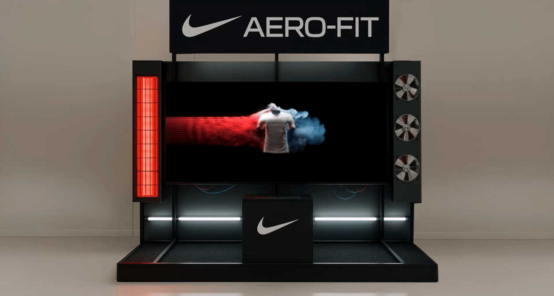 A Nike AERO-FIT display by FutureDeluxe features a digital screen showing a white shirt with red and blue airflow effects, surrounded by fans on the right and a red heat lamp on the left, all set against a sleek, black background. Frame from Stash Magazine article.