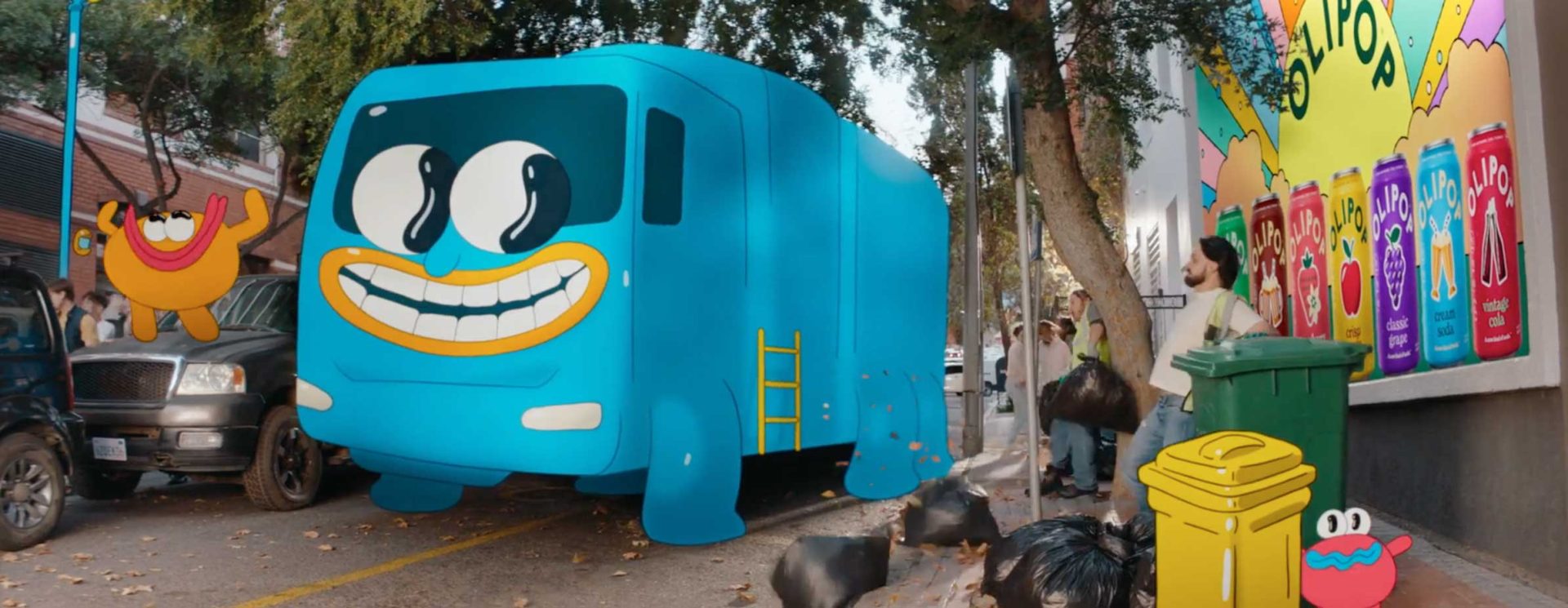 A bright blue cartoon-style truck with a smiling face, featuring OLIPOP artwork by Luca&Sinem, is parked on a city street. Animated characters and colorful cans adorn the wall as people toss garbage into bins nearby. Trees and cars line the street. Frame from Stash Magazine article.