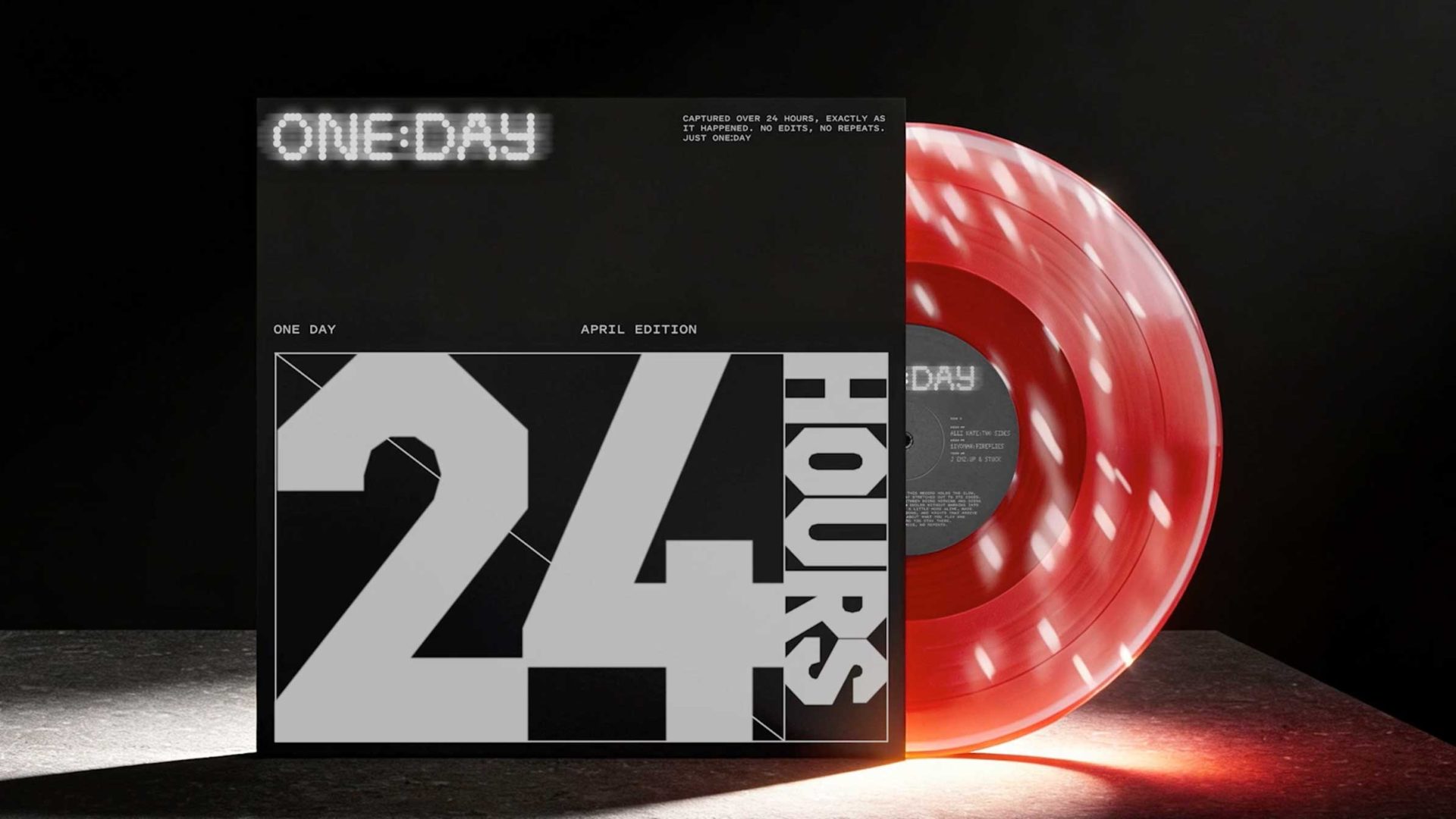 A red and white marbled vinyl record stands upright next to its black cover, featuring bold white text reading 24 HOURS and ONE DAY in a modern, digital style—perfect for when the countdown begins and you can Never Sit Still. Light shines dramatically from the right. Frame from Stash Magazine article.