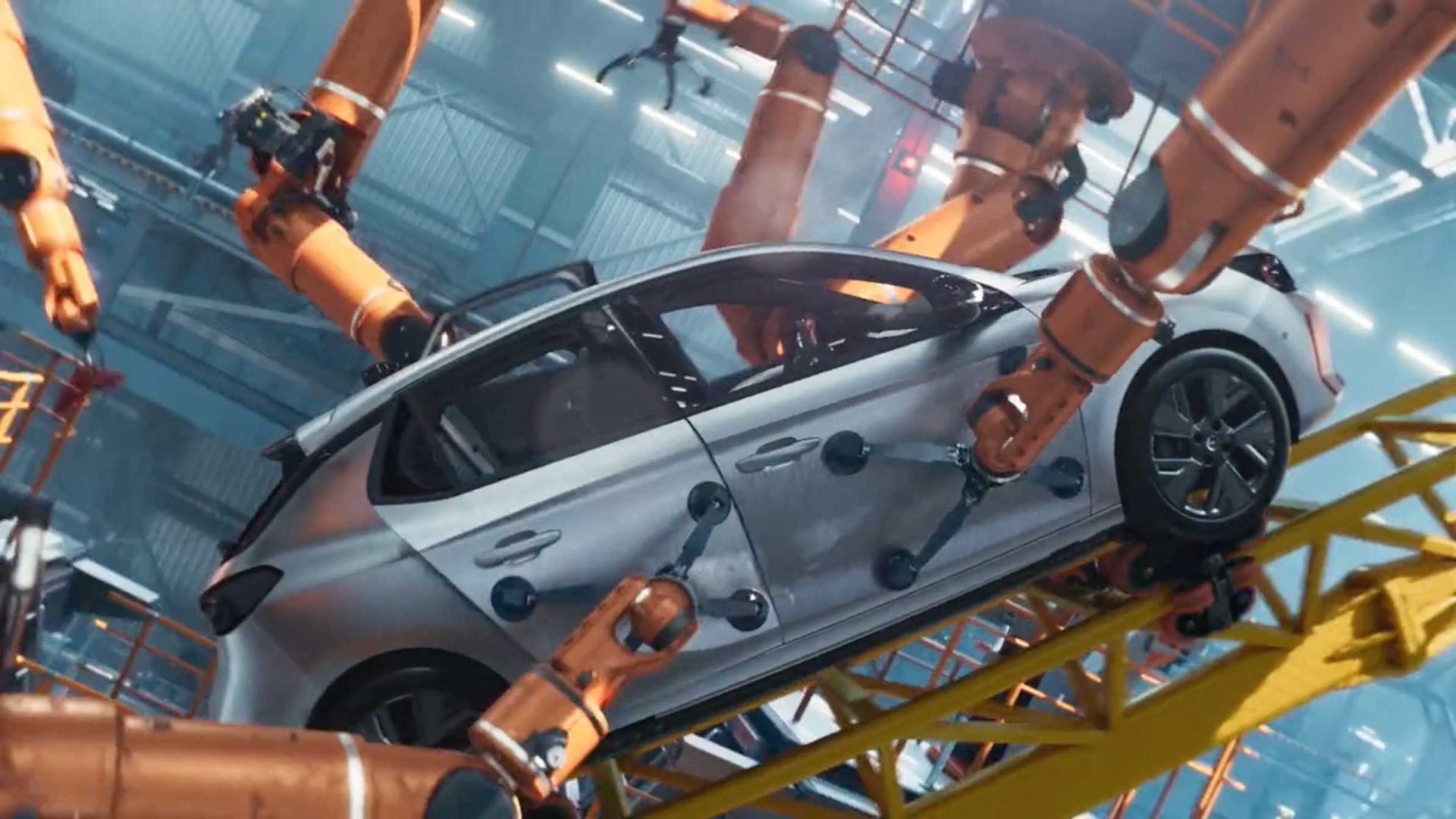 A silver car, reminiscent of the Opel Corsa roller Coaster commercial by Mark Jenkinson LA PAC & Mathematic, is surrounded by orange robotic arms in an automotive factory, as the robots assemble or inspect the vehicle on an angled platform. Frame from Stash Magazine article.