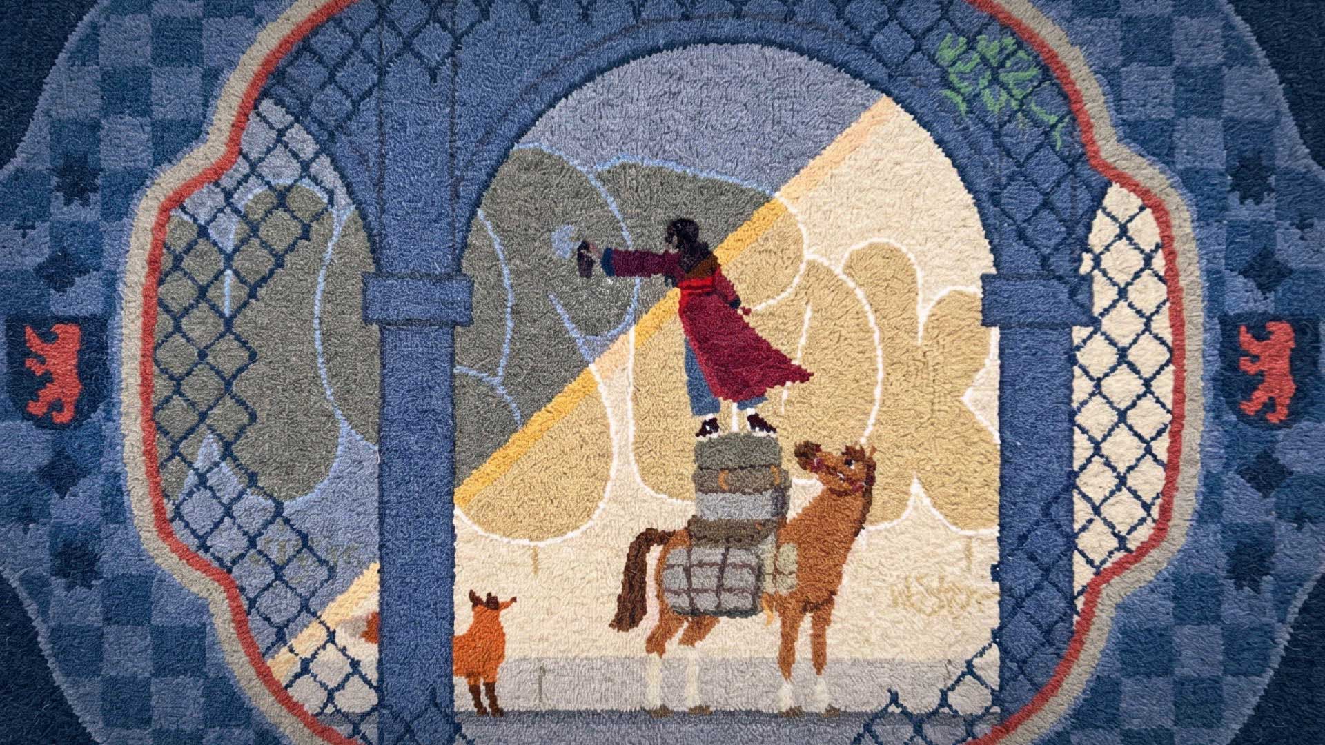 A stylized rug by Natalia Bazina shows a person in a red robe standing on stacked bundles next to a camel and a goat, framed by blue arches and a patterned border with lion motifs, capturing WOSTOK’s signature artistic flair. Frame from Stash Magazine article.