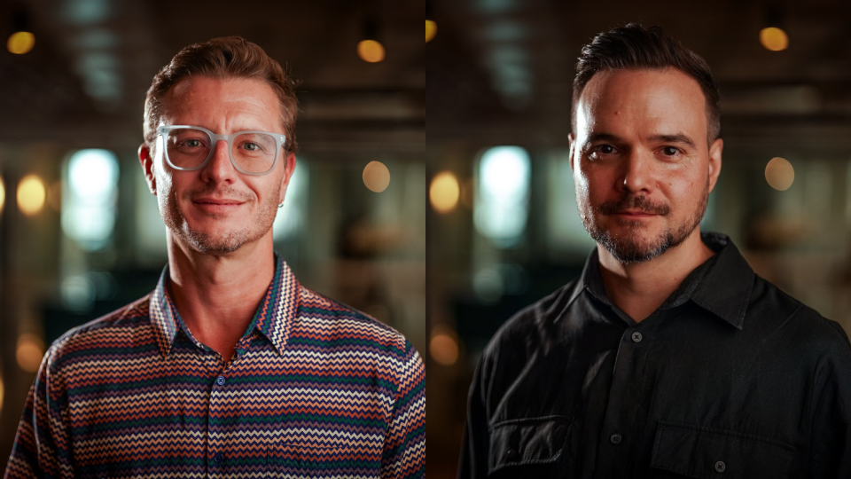 Two men are shown in side-by-side portraits, both indoors with blurred warm lighting in the background. The man on the left, Robert Bruce, wears glasses and a patterned shirt; the man on the right, Theuns Van Rensburg—renowned for his work in VFX—has a beard and wears a dark shirt. Frame from Stash Magazine article.