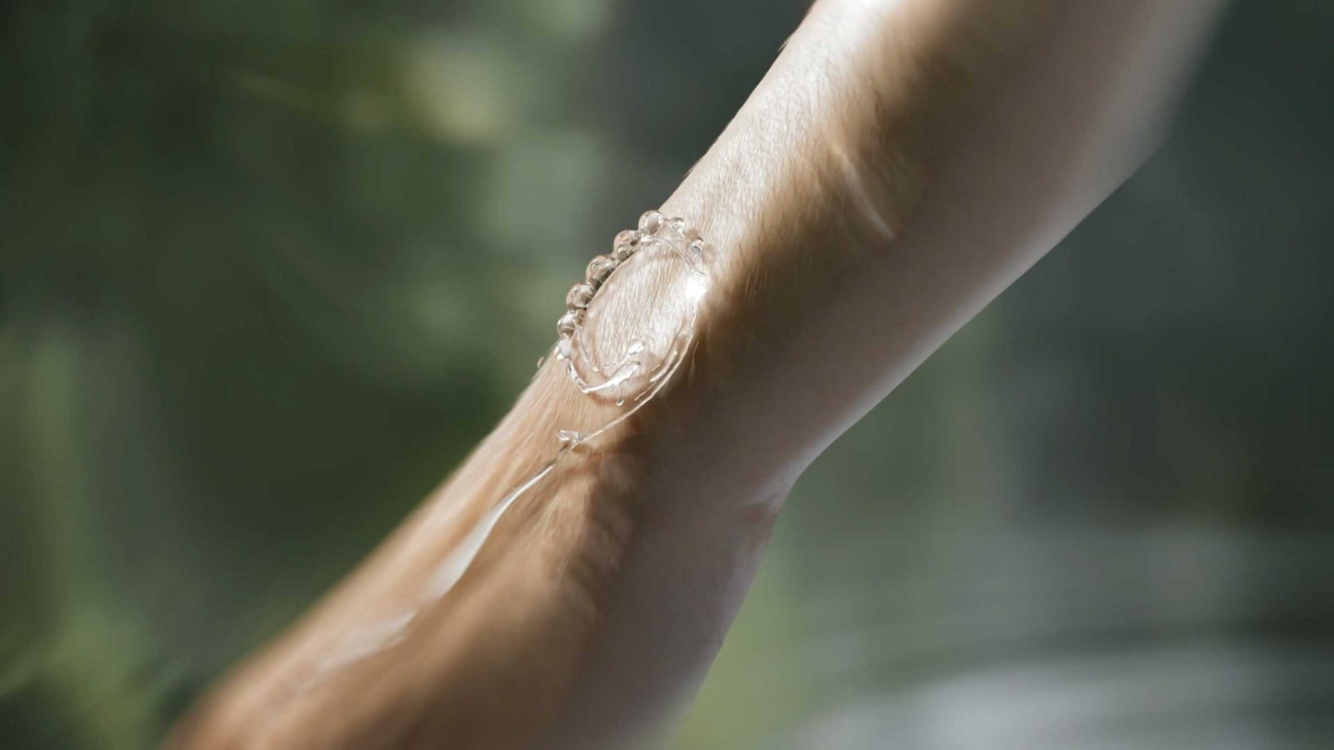 A close-up of a person’s forearm with a clear gel or serum being applied to the skin, against a soft, blurred green background—an elegant moment reminiscent of Roger Dubuis luxury and care. Frame from Stash Magazine article.