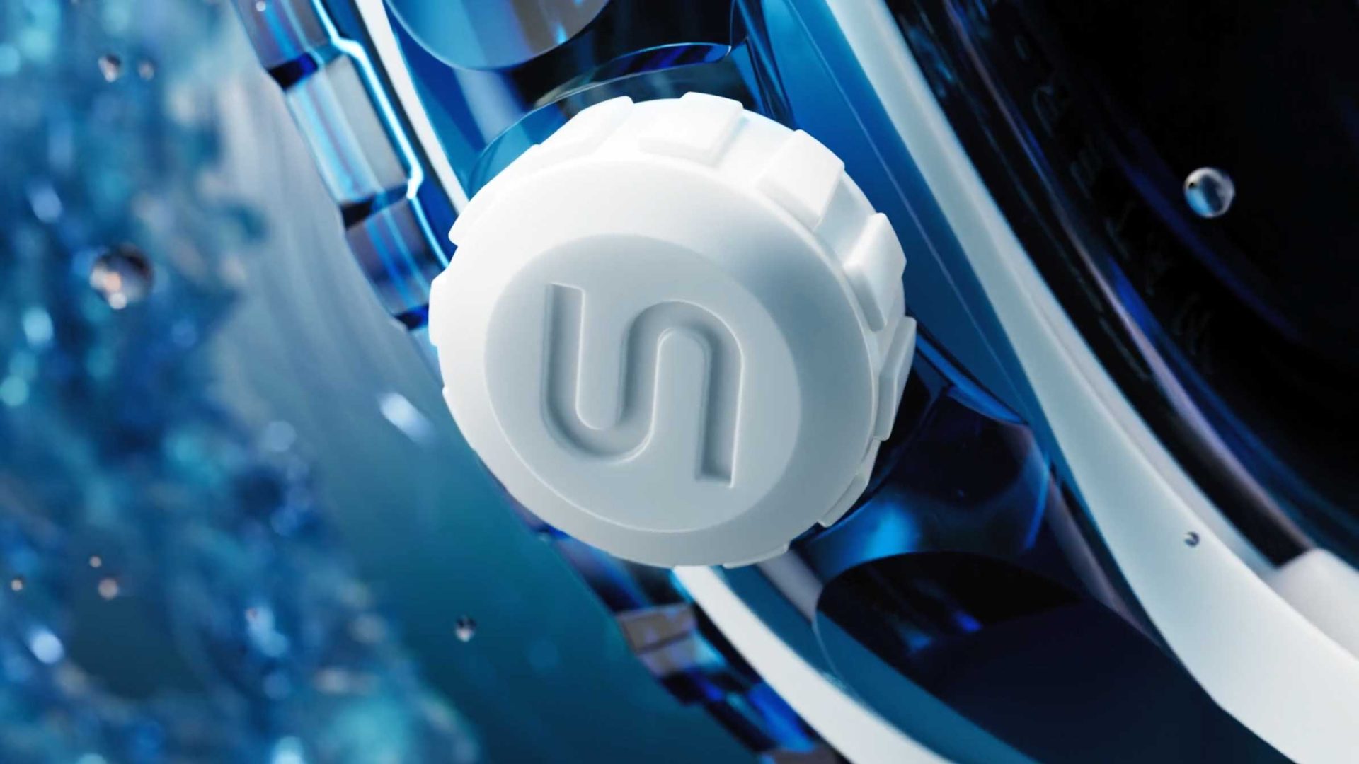 A close-up of a white, ridged MOX knob with an embossed S logo, attached to a shiny blue metallic surface from Dada Projects, with water splashing on the left side. Frame from Stash Magazine article.