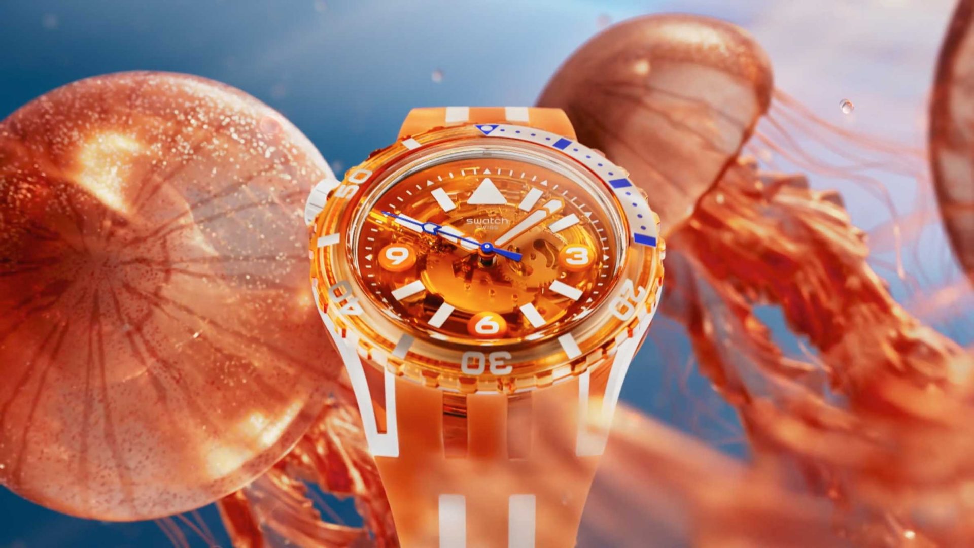 An orange and white Swatch wristwatch with a transparent face is displayed underwater, surrounded by floating jellyfish in a blue aquatic background. Frame from Stash Magazine article.